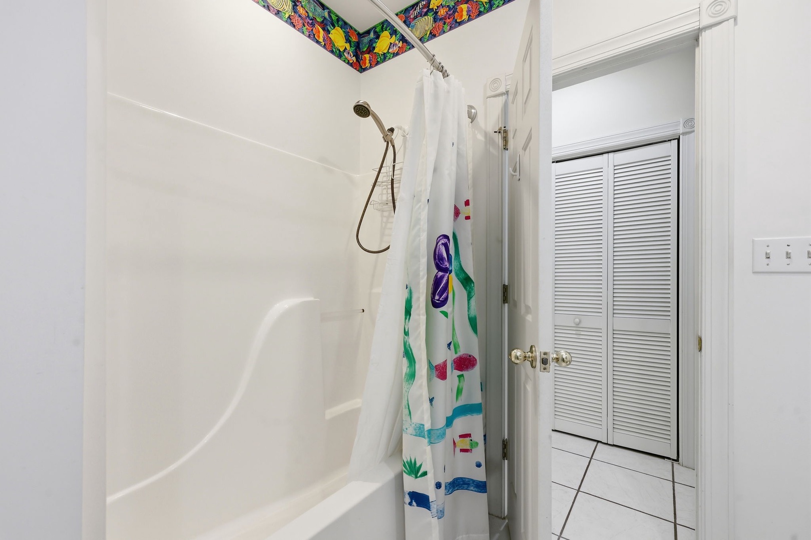Freshen up in your clean, bright bathroom with a full tub-shower combo and playful tropical accents above, bringing a splash of island charm to your daily routine.