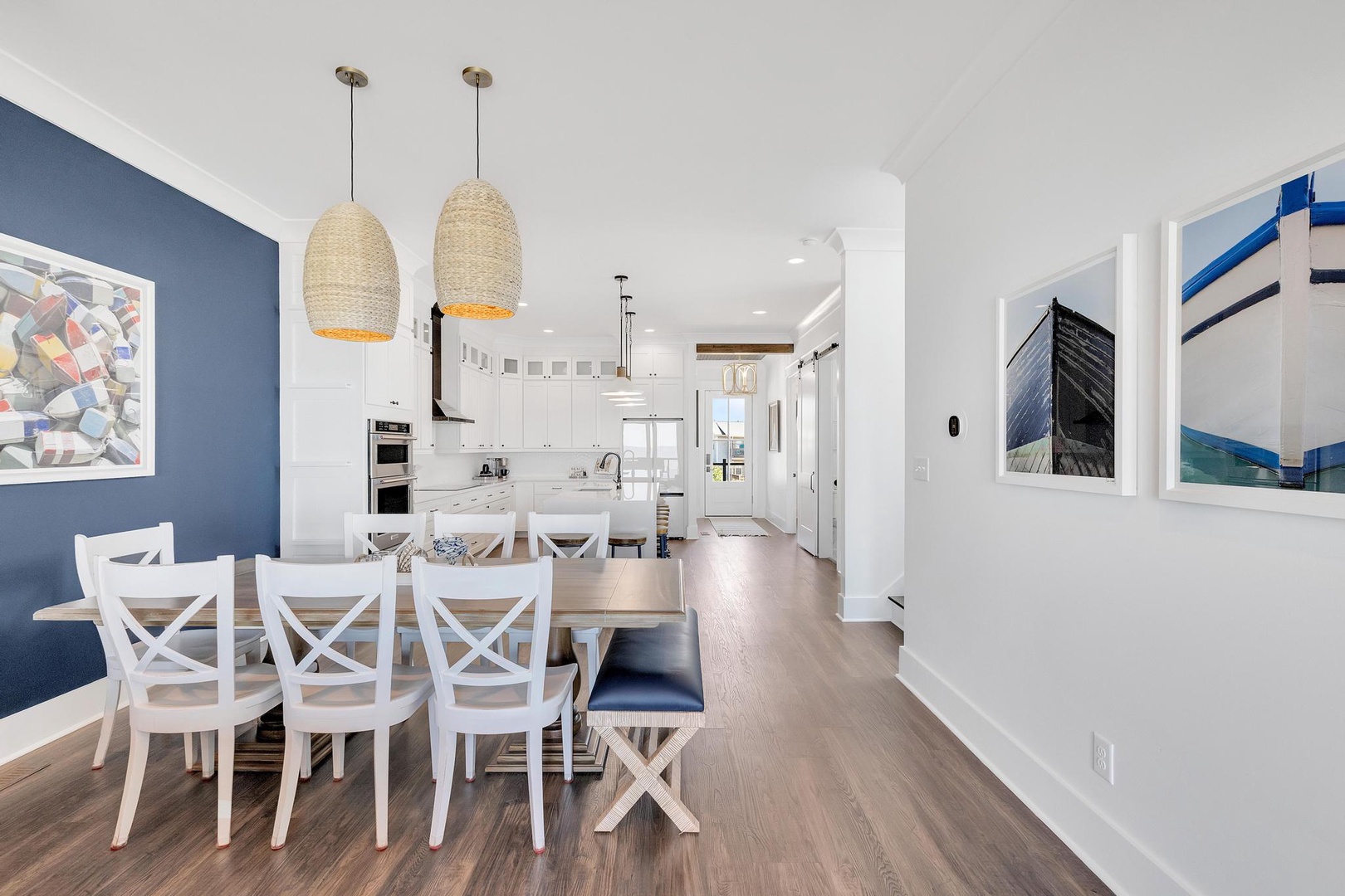Picture yourself gathered around this inviting dining table, sharing meals with loved ones beneath the warm glow of woven pendant lights. The open layout flows seamlessly into your fully-equipped kitchen, perfect for coastal living.