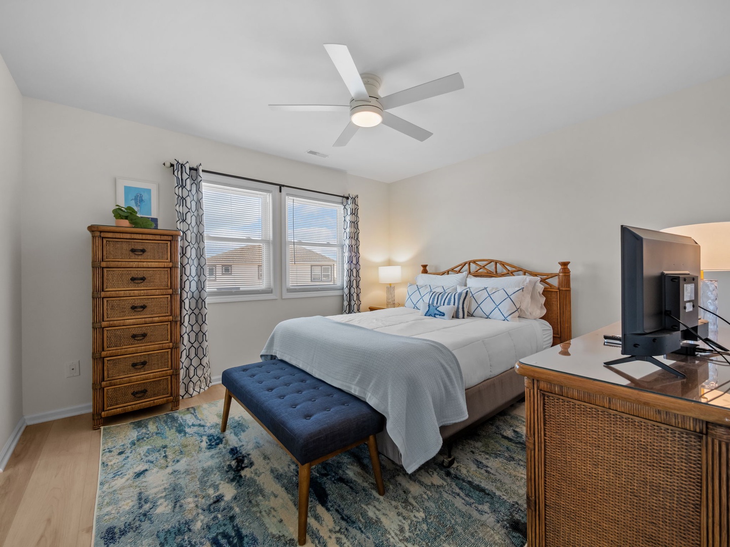 Unwind in your peaceful bedroom featuring coastal-inspired furnishings, a comfortable king bed, and gentle ceiling fan keeping you cool.