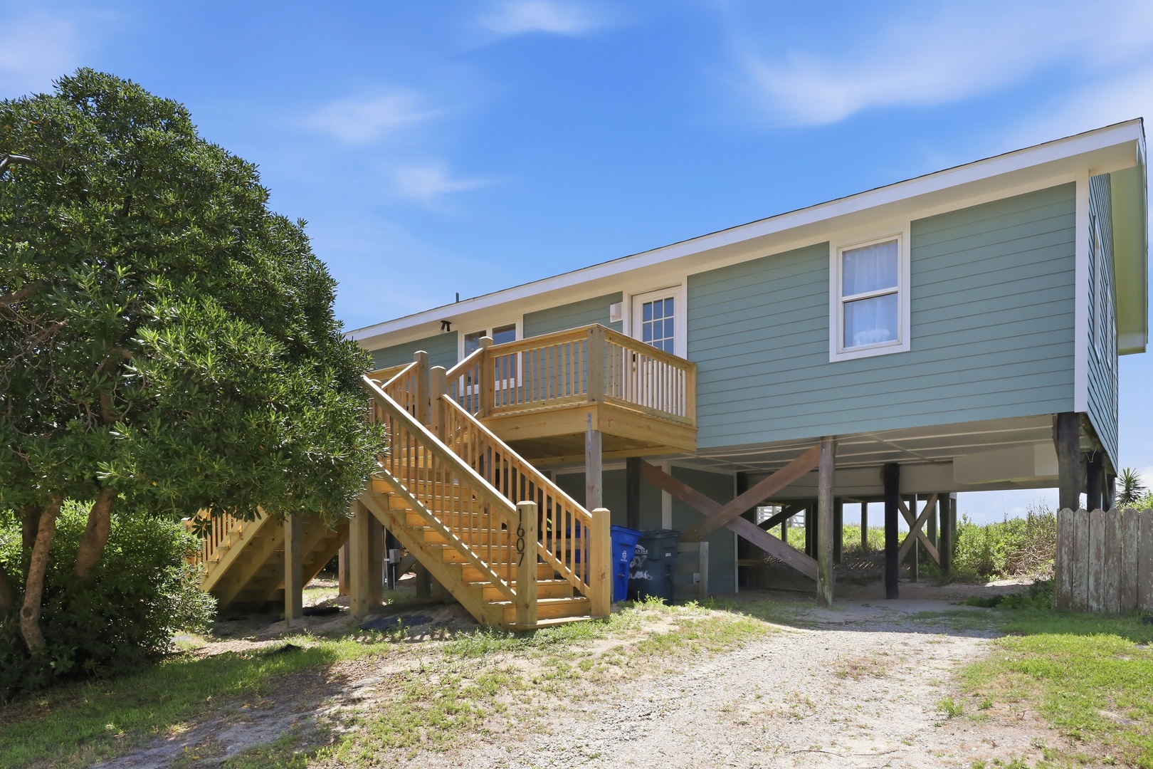 Elevated beachside retreat with covered parking and private deck, surrounded by coastal greenery and just steps from the shore.