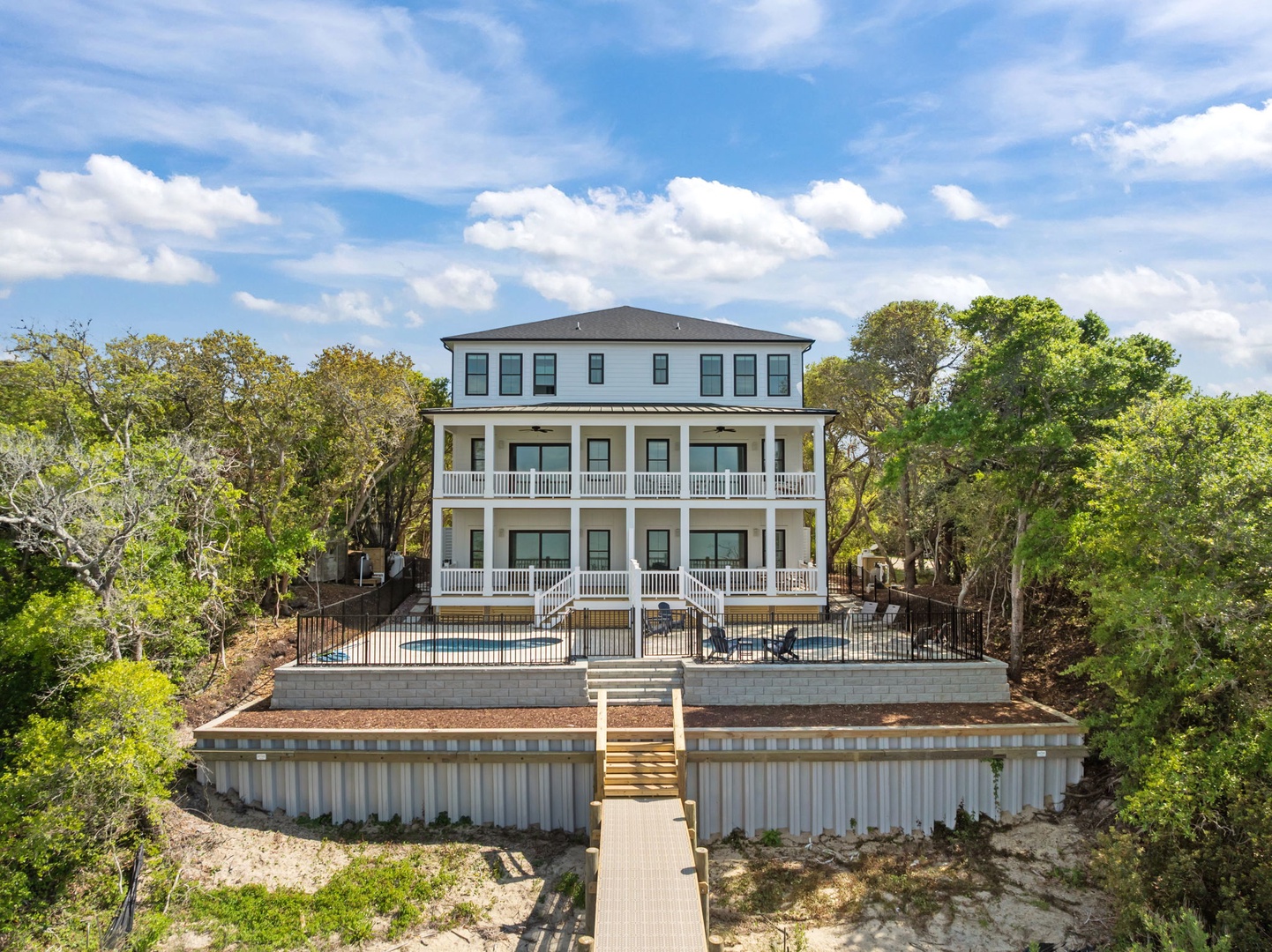 This stunning three-story waterfront home sits majestically among mature trees, featuring private pool access and elevated terraces for ultimate relaxation.