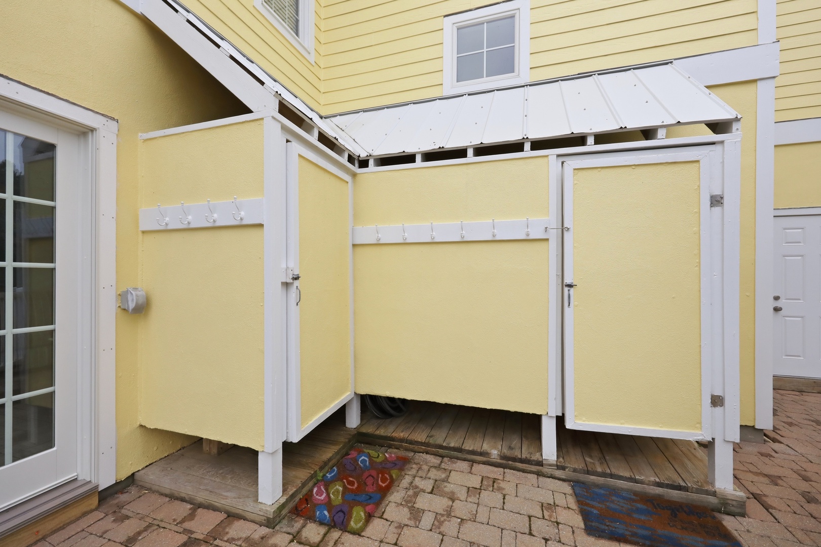 A covered outdoor shower enclosure provides a practical rinse-off spot with privacy screens, easy access from the patio, and thoughtful weather protection overhead.