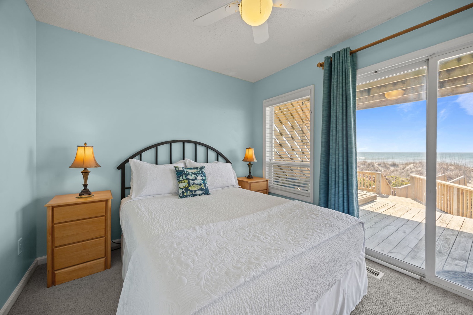 Wake up to ocean views through your private balcony doors in this serene coastal bedroom.