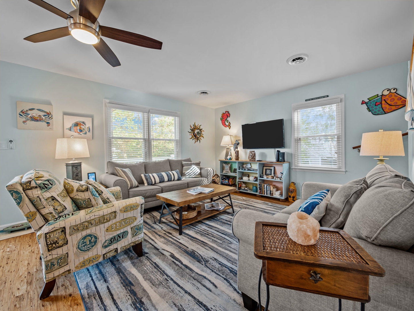 Unwind in your cheerful living room with plush seating, playful coastal decor, and natural light streaming through windows.