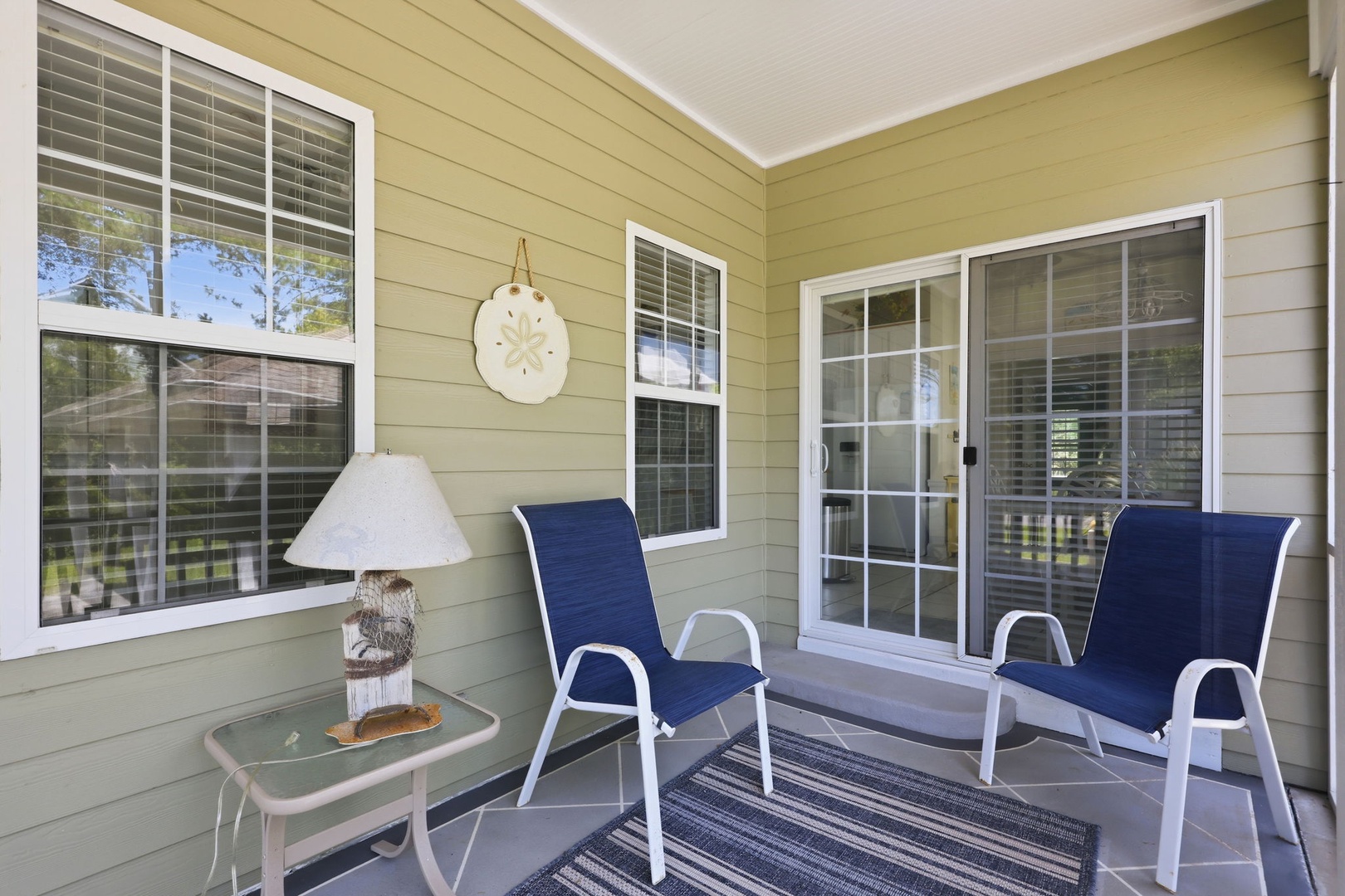 Covered porch with comfortable seating and nautical decor, offering a shaded spot to relax with your morning coffee or unwind after a day of beach adventures.