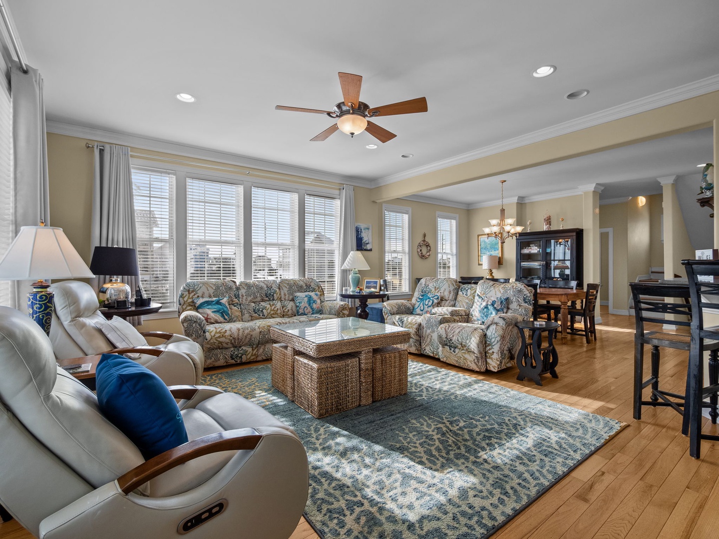 Relax in this spacious living room with comfortable seating, warm natural light streaming through large windows, and an open layout perfect for gathering.