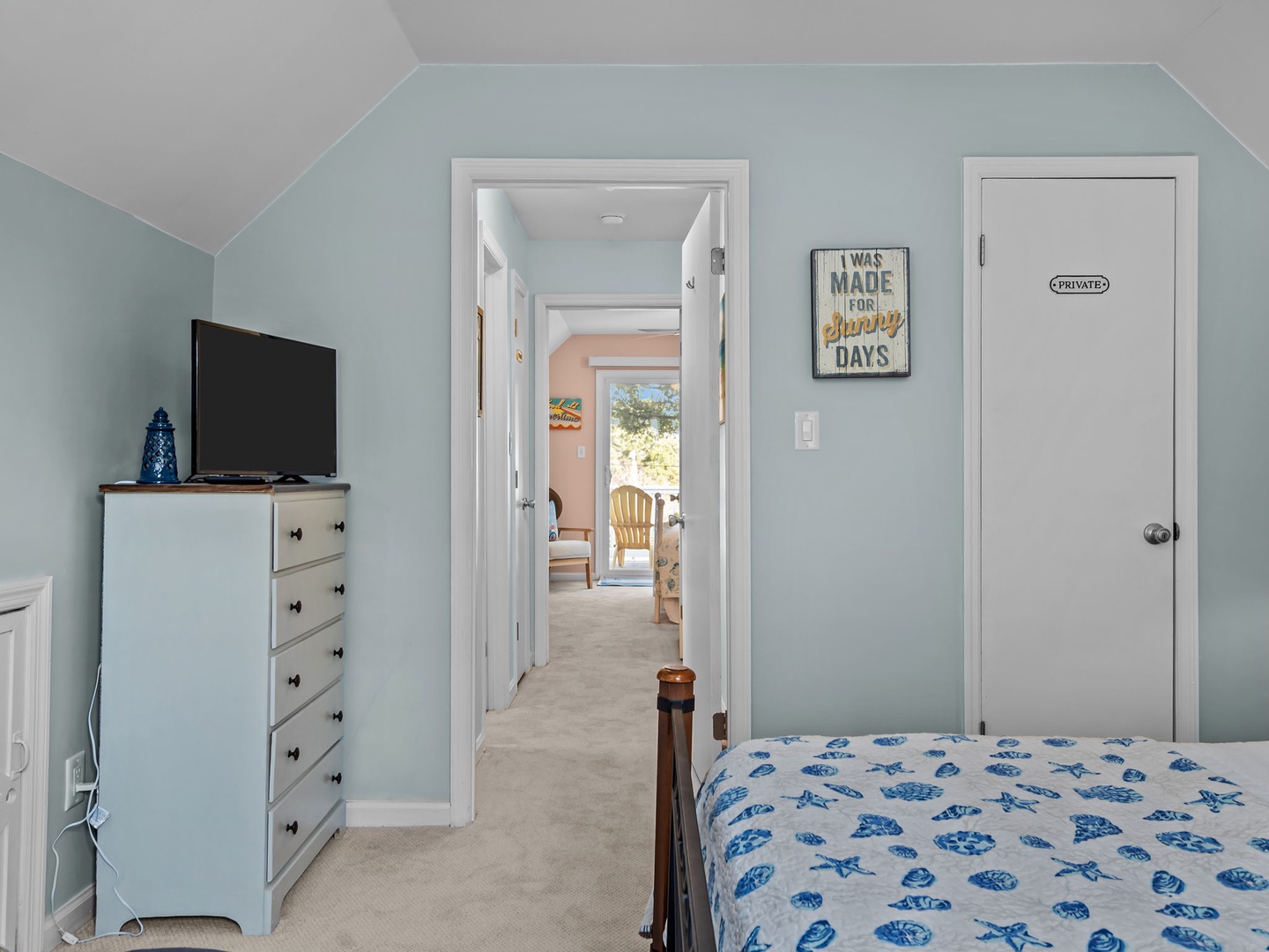 Your bright bedroom features a wall-mounted TV, spacious dresser, and charming coastal decor creating the perfect retreat for restful nights.