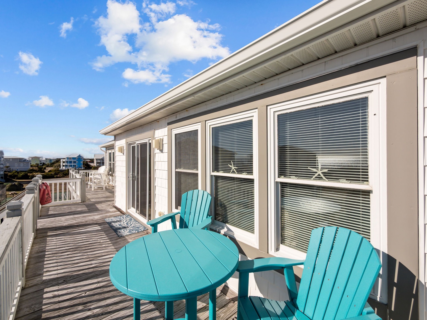 Relax on your private deck with turquoise coastal-style chairs and table, soaking in the neighborhood views.
