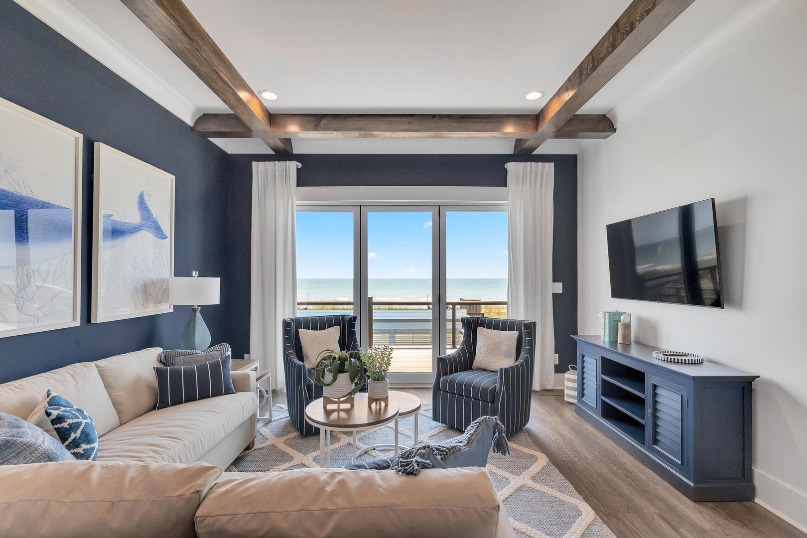 You'll love unwinding in this coastal living room, where rustic beams frame stunning ocean views beyond your private balcony. Sink into soft seating after a day at the beach and enjoy the calming palette of blues and creams.