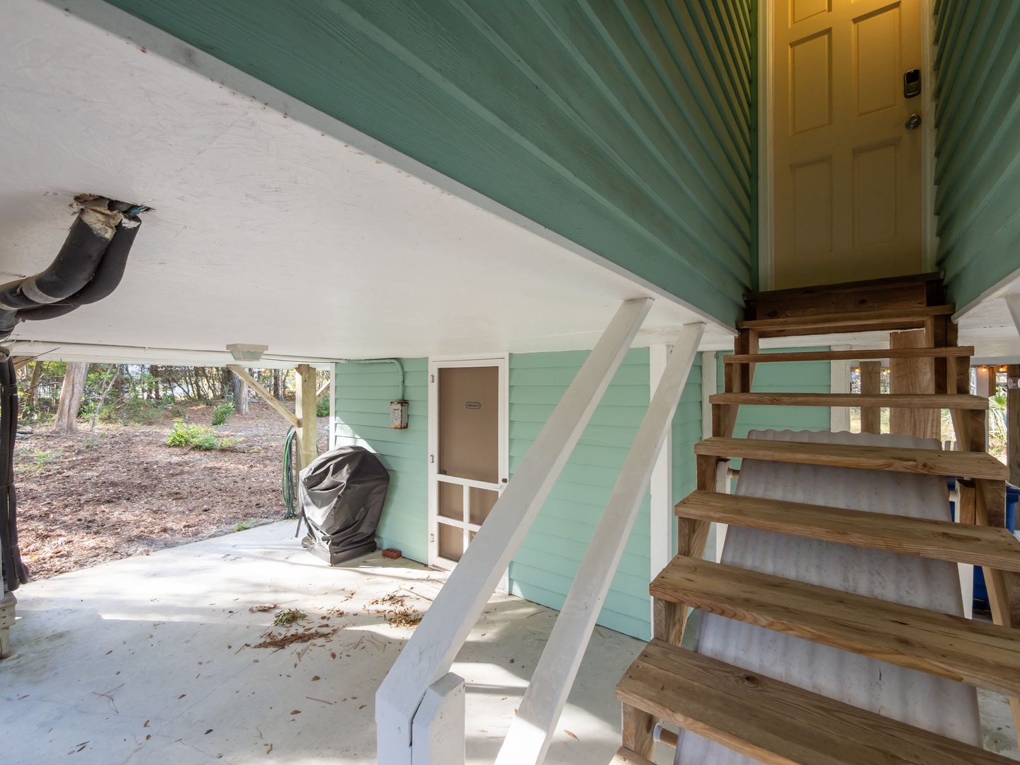 Ground-level covered area with storage and outdoor stairs leading to your beachside retreat.