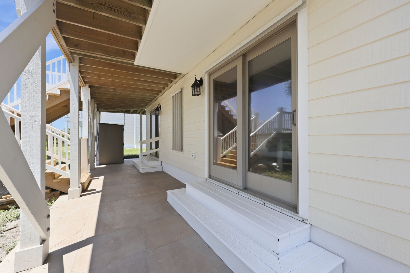 A covered walkway leads to sliding glass doors, offering a quiet outdoor area for relaxing and enjoying the surroundings.