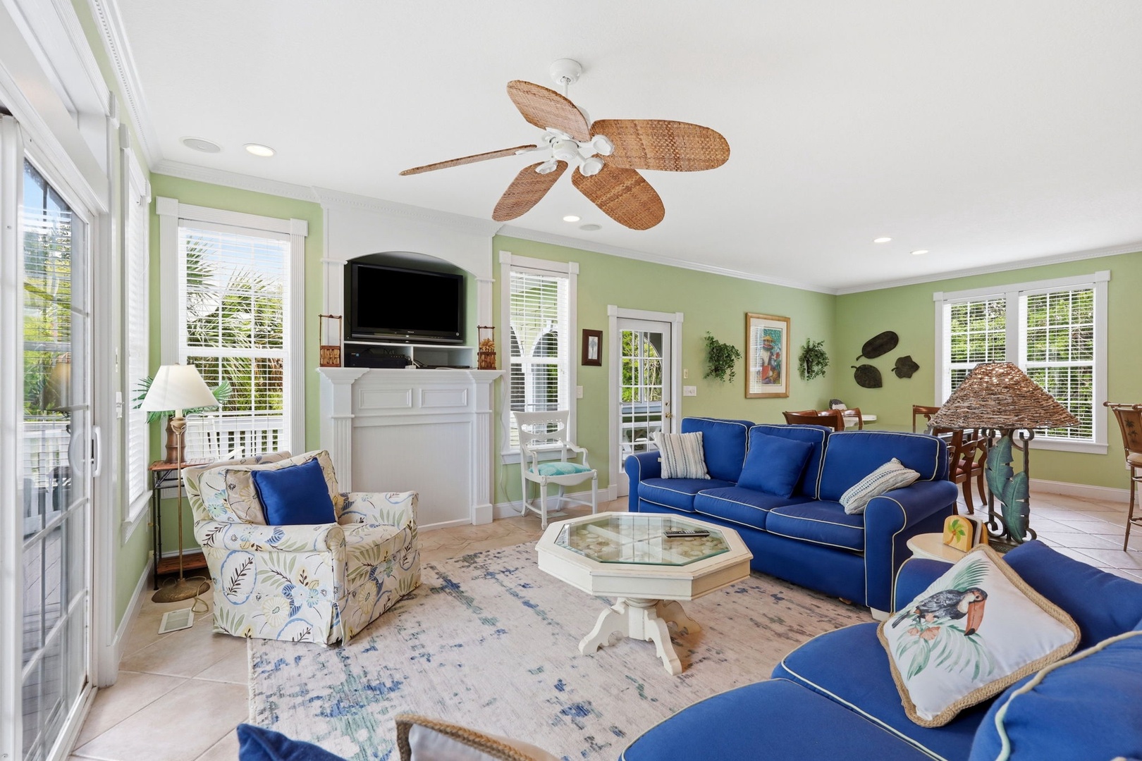 Sink into plush coastal comfort and unwind in this sun-drenched living space, where calming hues and breezy ceiling fans create your perfect island retreat.