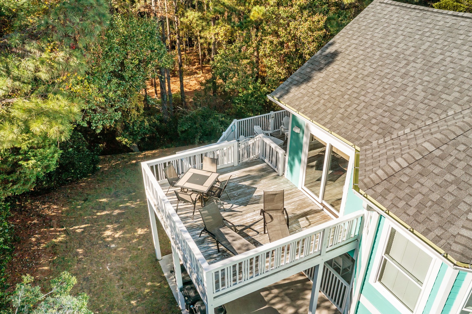 Aerial view of the property's elevated deck featuring outdoor seating surrounded by lush forest canopy.