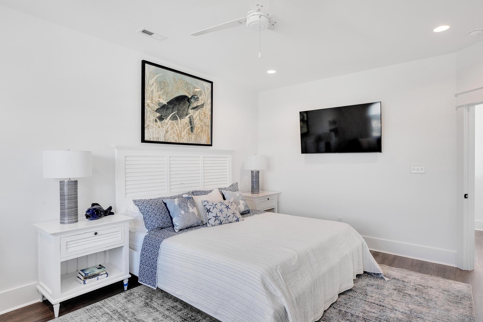 Drift off to sleep in this serene coastal bedroom with crisp white linens, a large flatscreen TV, and plush carpeting underfoot. Your private retreat awaits.