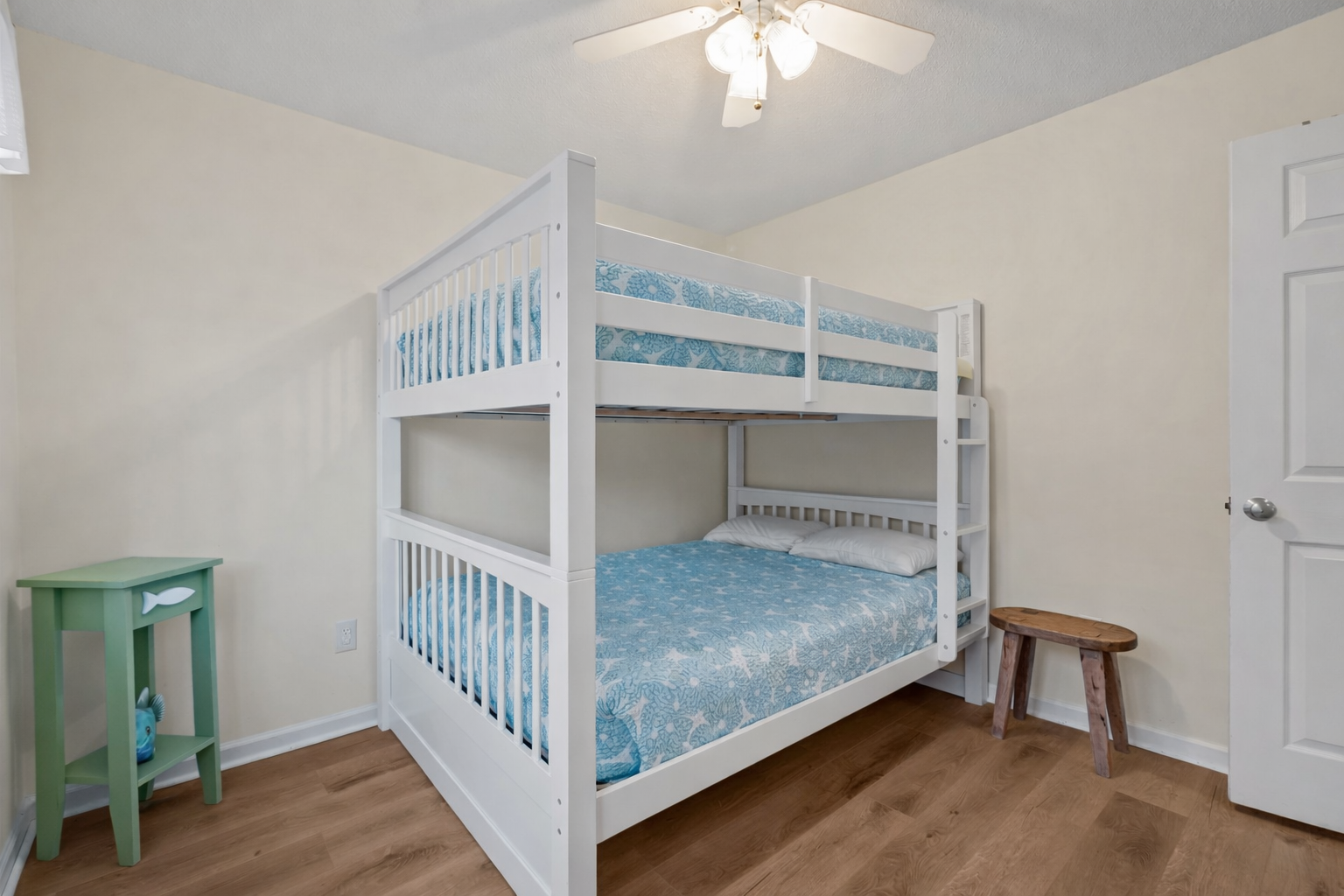Your kids will love this cheerful bunk bed room with ocean-blue bedding and warm wood floors for comfortable sleeps.