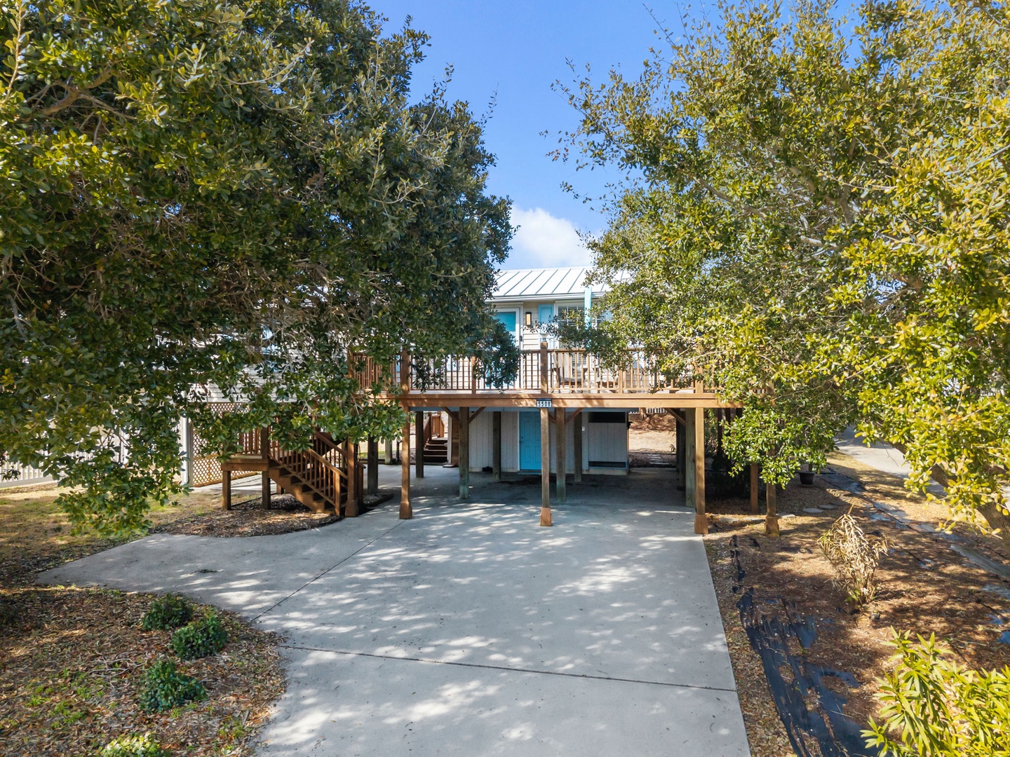 Charming elevated home nestled among mature trees with covered parking and outdoor deck areas.