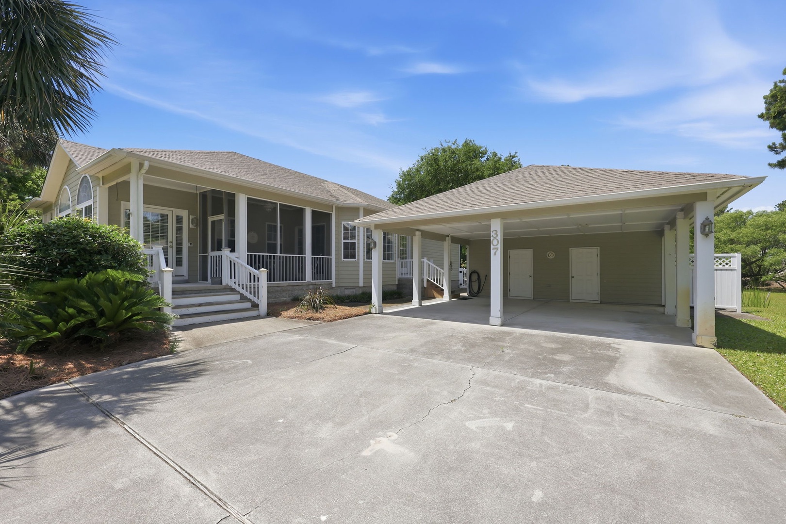 A charming single-story vacation home with covered carport, surrounded by mature landscaping and tropical palms in a quiet neighborhood—your coastal getaway awaits.