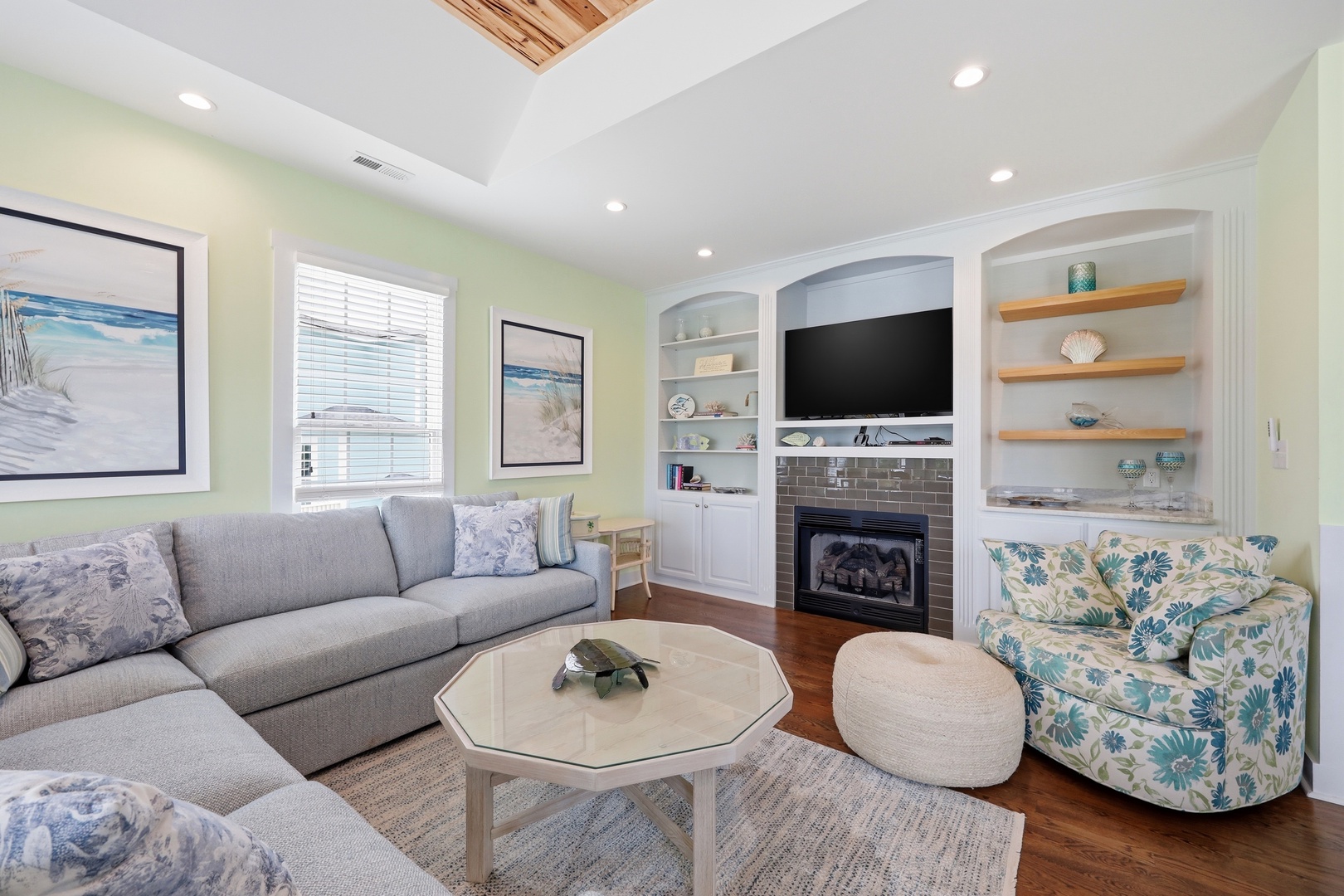 Settle into this bright, coastal living room where soft seating, a cozy fireplace, and beach-inspired decor invite you to unwind after a day of exploring.