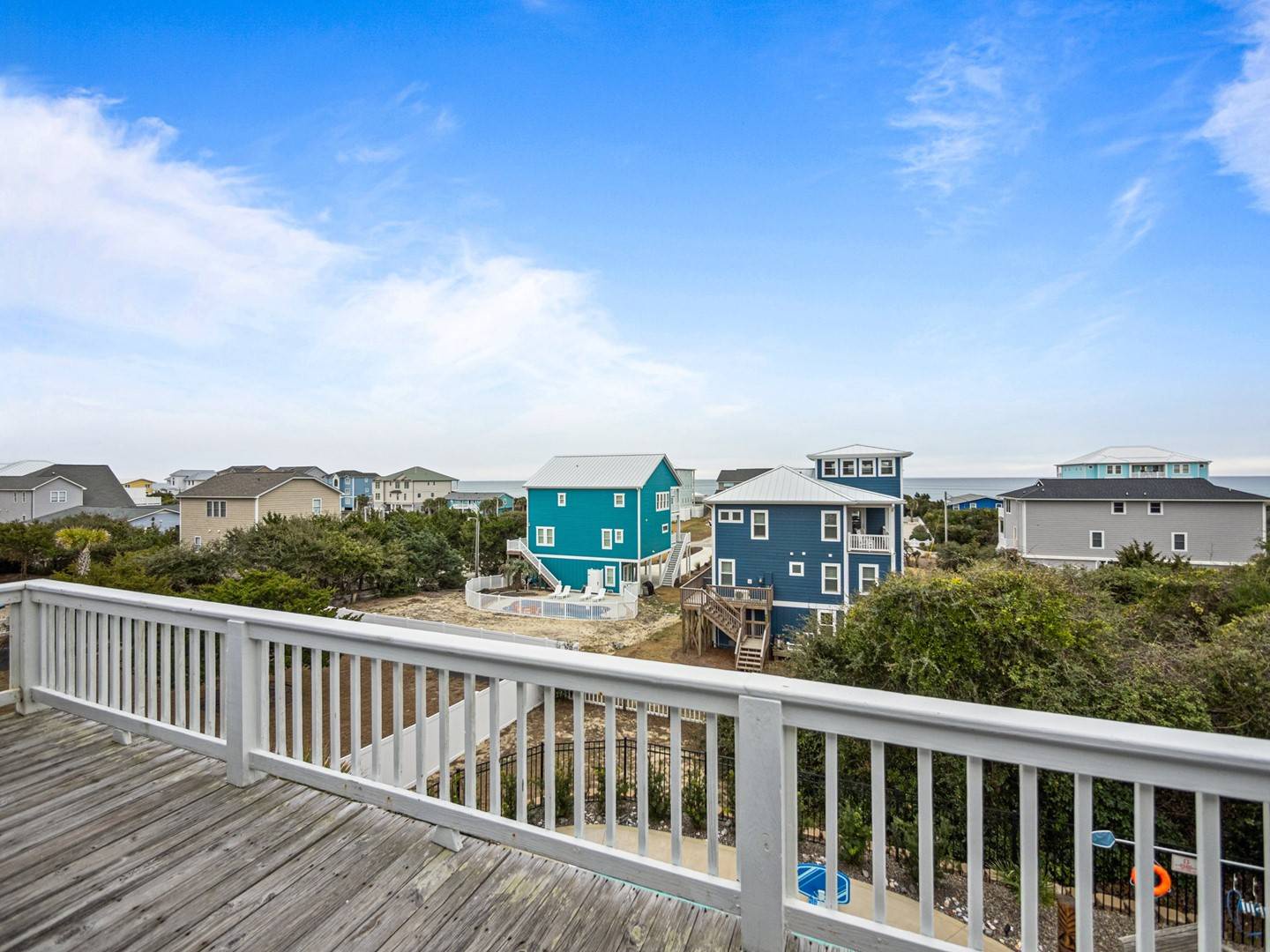 Peaceful coastal neighborhood with colorful beach houses stretching toward the horizon under endless blue skies.