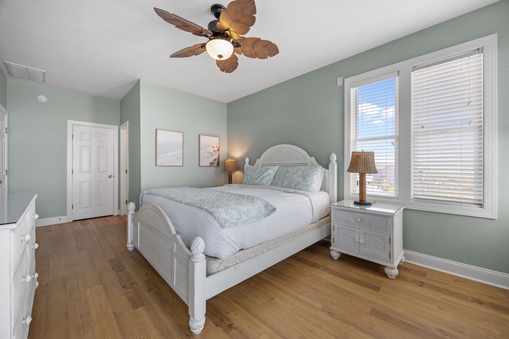 Your peaceful bedroom features crisp white coastal furniture, soothing seafoam walls, and tropical ceiling fan creating the perfect retreat for restful nights.