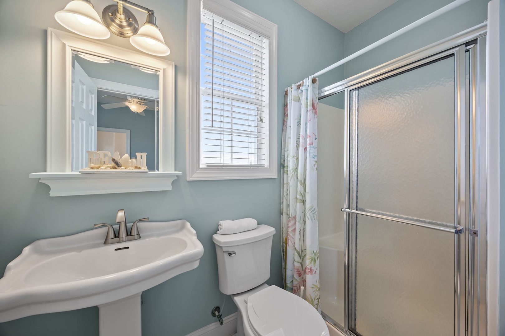 Refresh in your serene bathroom with soft aqua walls, classic fixtures, and natural light filtering through the window.