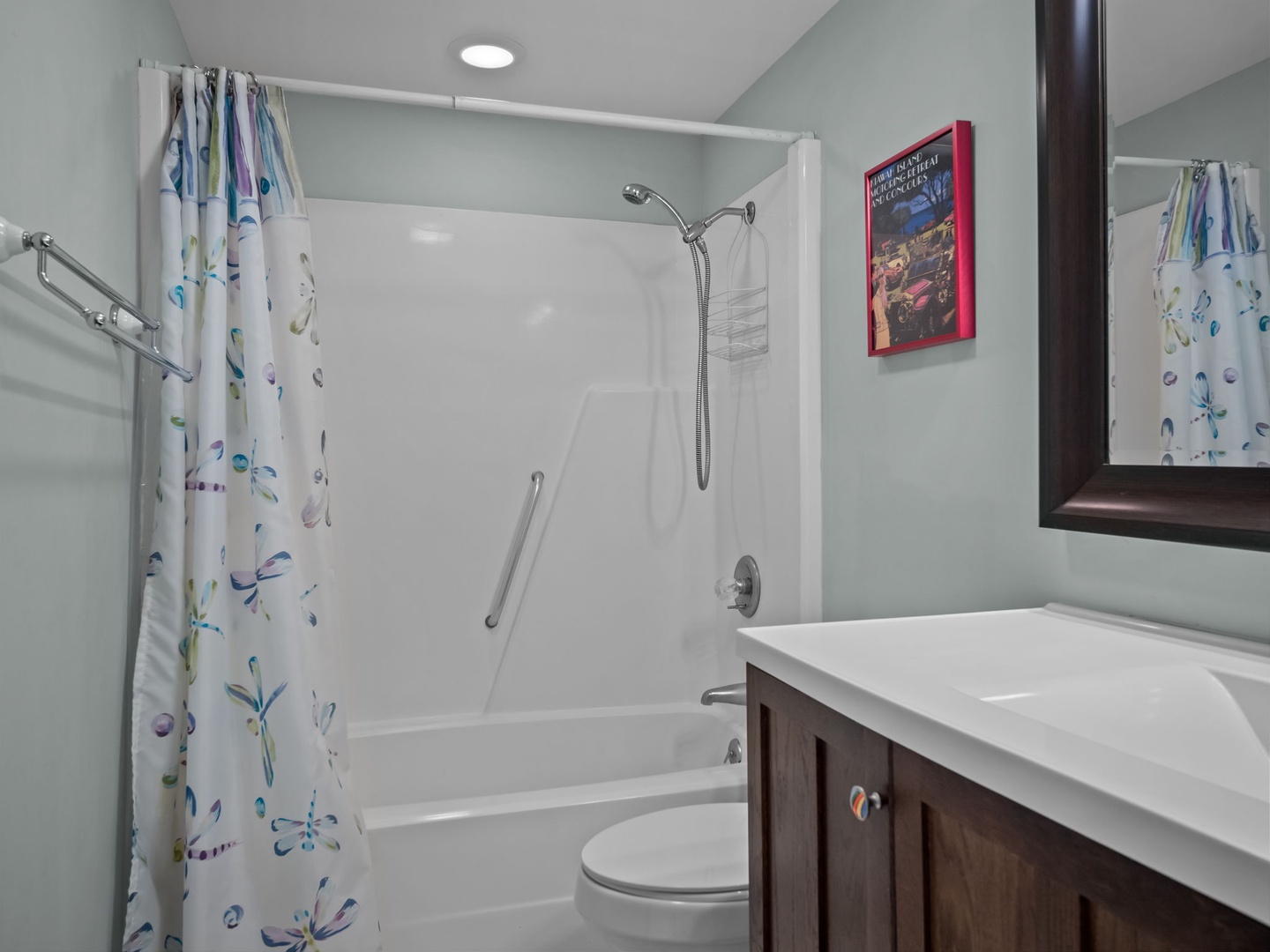Step into your bright, accessible bathroom featuring a comfortable tub-shower combo with safety rails and cheerful floral curtains.