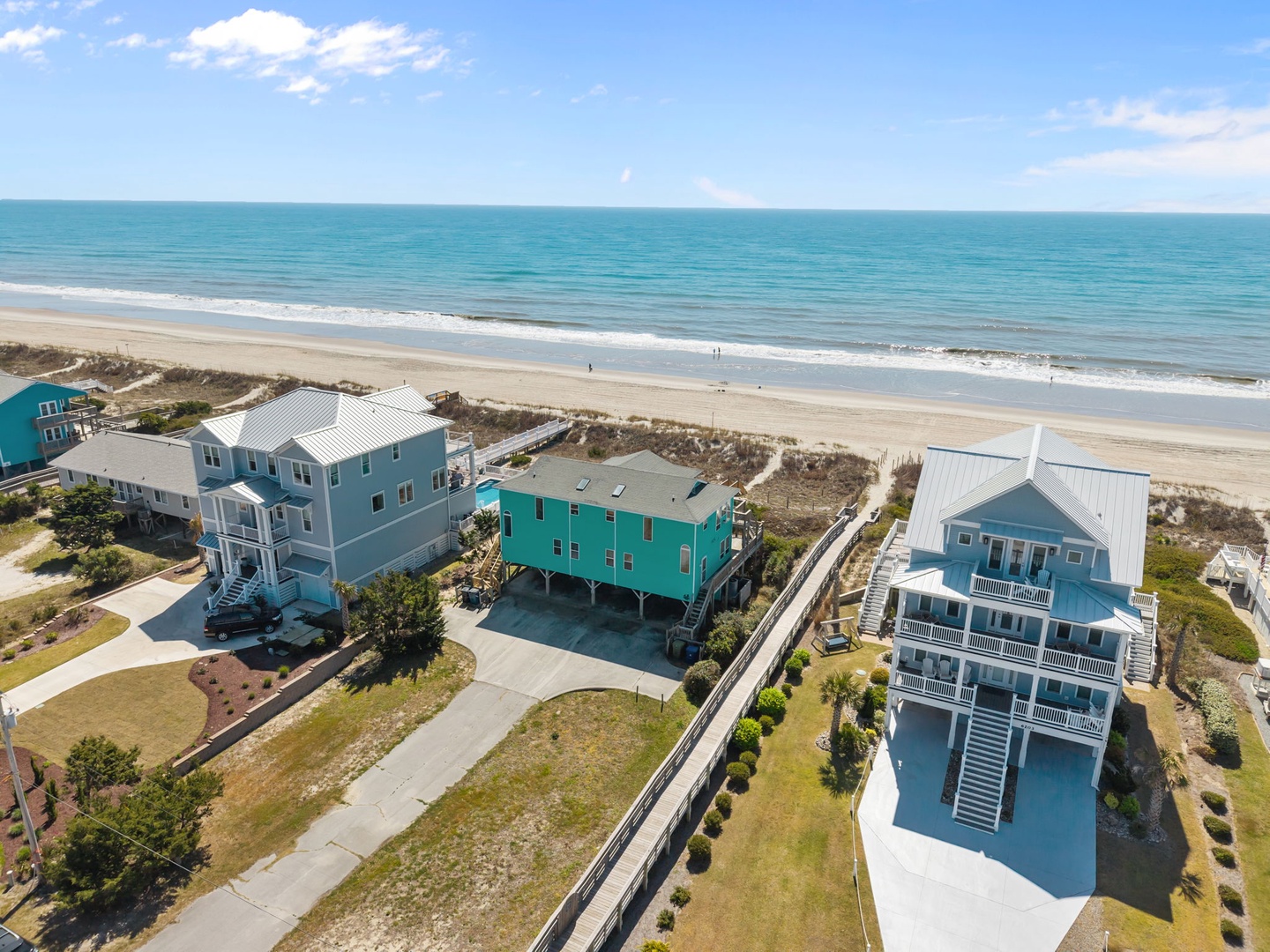 Colorful beachfront rental homes positioned steps from pristine sandy shores and turquoise waters.