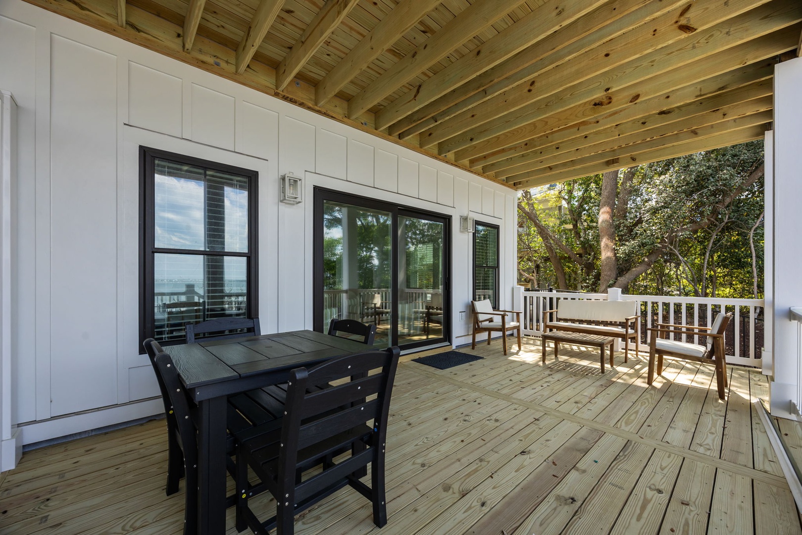 Your private covered deck offers peaceful dining under exposed beams, with comfortable seating overlooking mature trees.