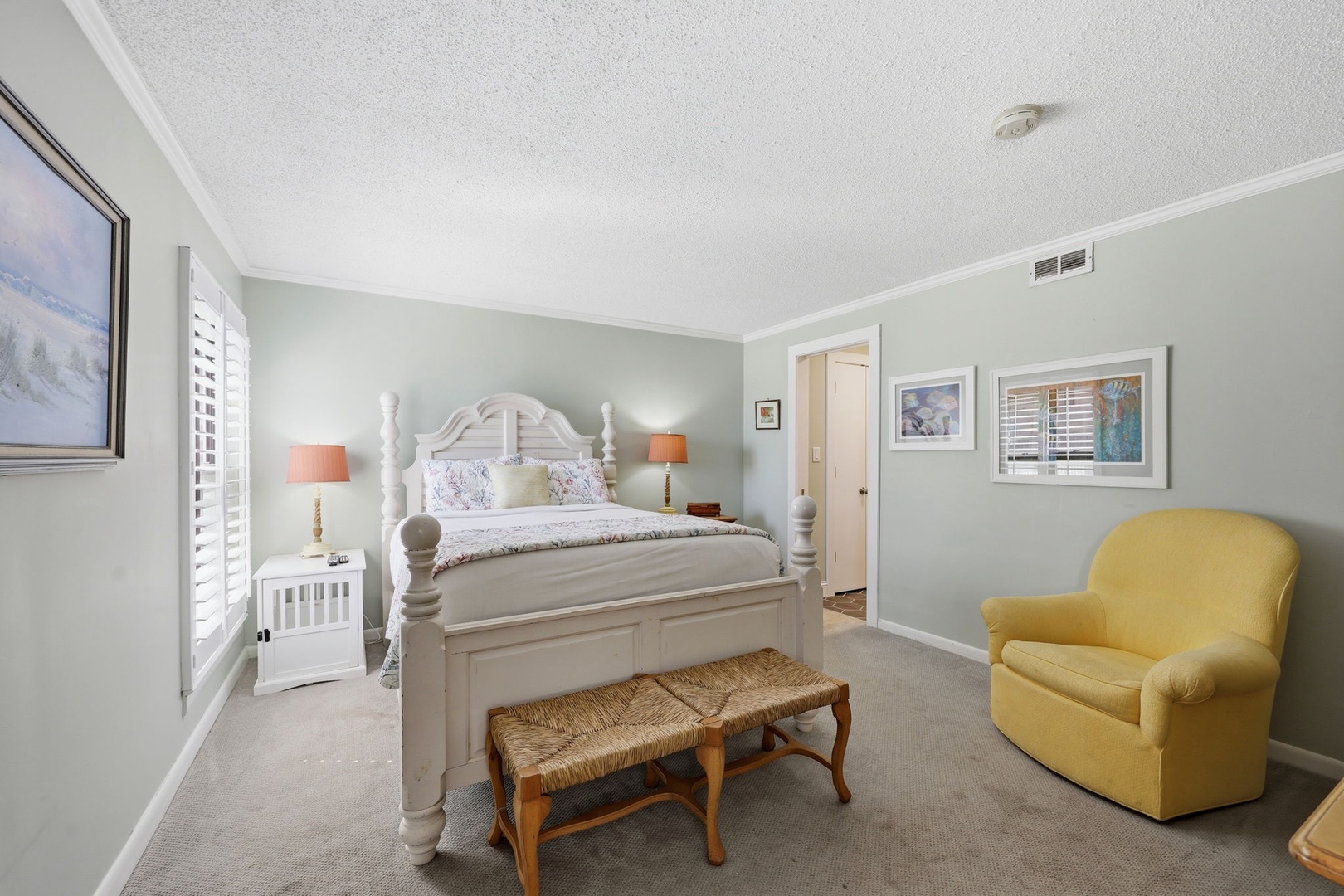 Sink into soft coastal comfort in your serene bedroom, where a charming four-poster bed, cozy seating, and soothing colors create your perfect retreat.