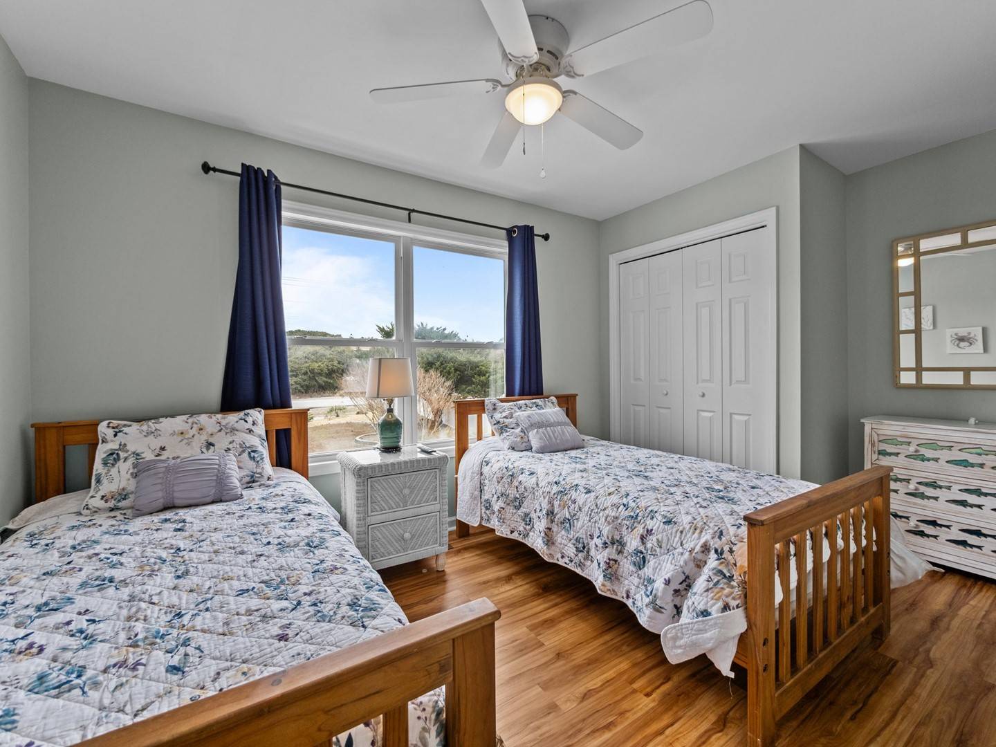 Your peaceful twin bedroom features comfortable beds with coordinated linens, natural light from large windows, and views of the surrounding landscape.
