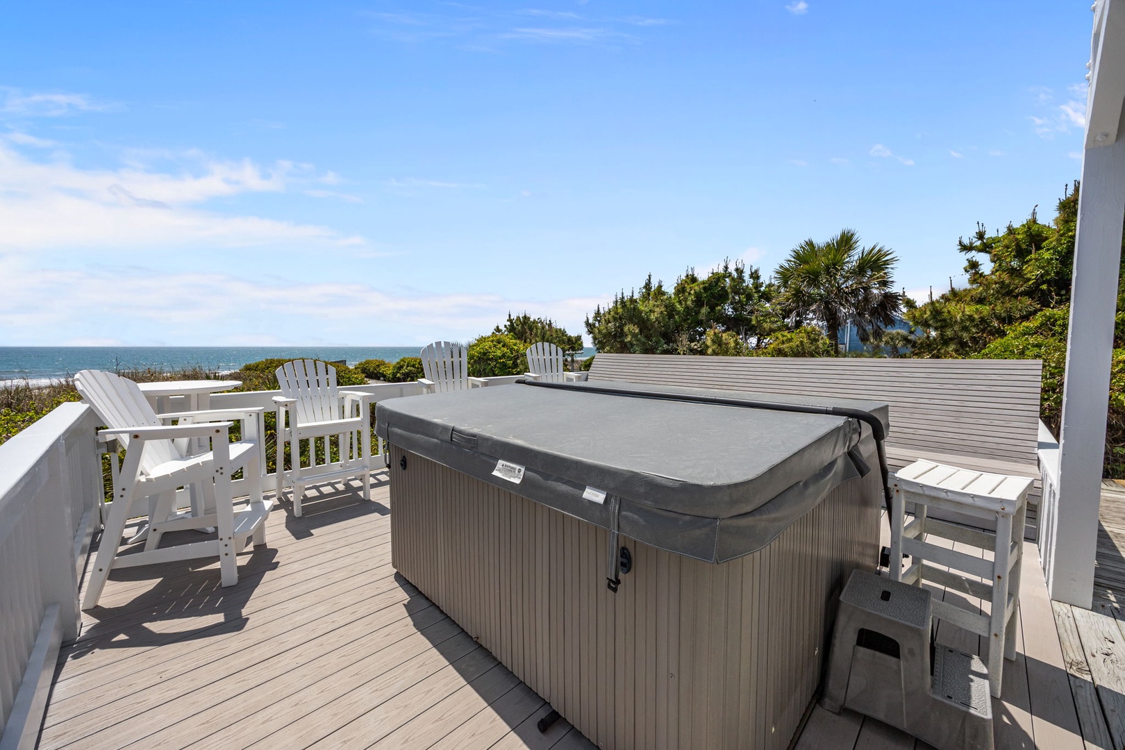 Spacious deck features a covered hot tub and oceanfront seating, perfect for relaxing while enjoying coastal breezes and sea views.