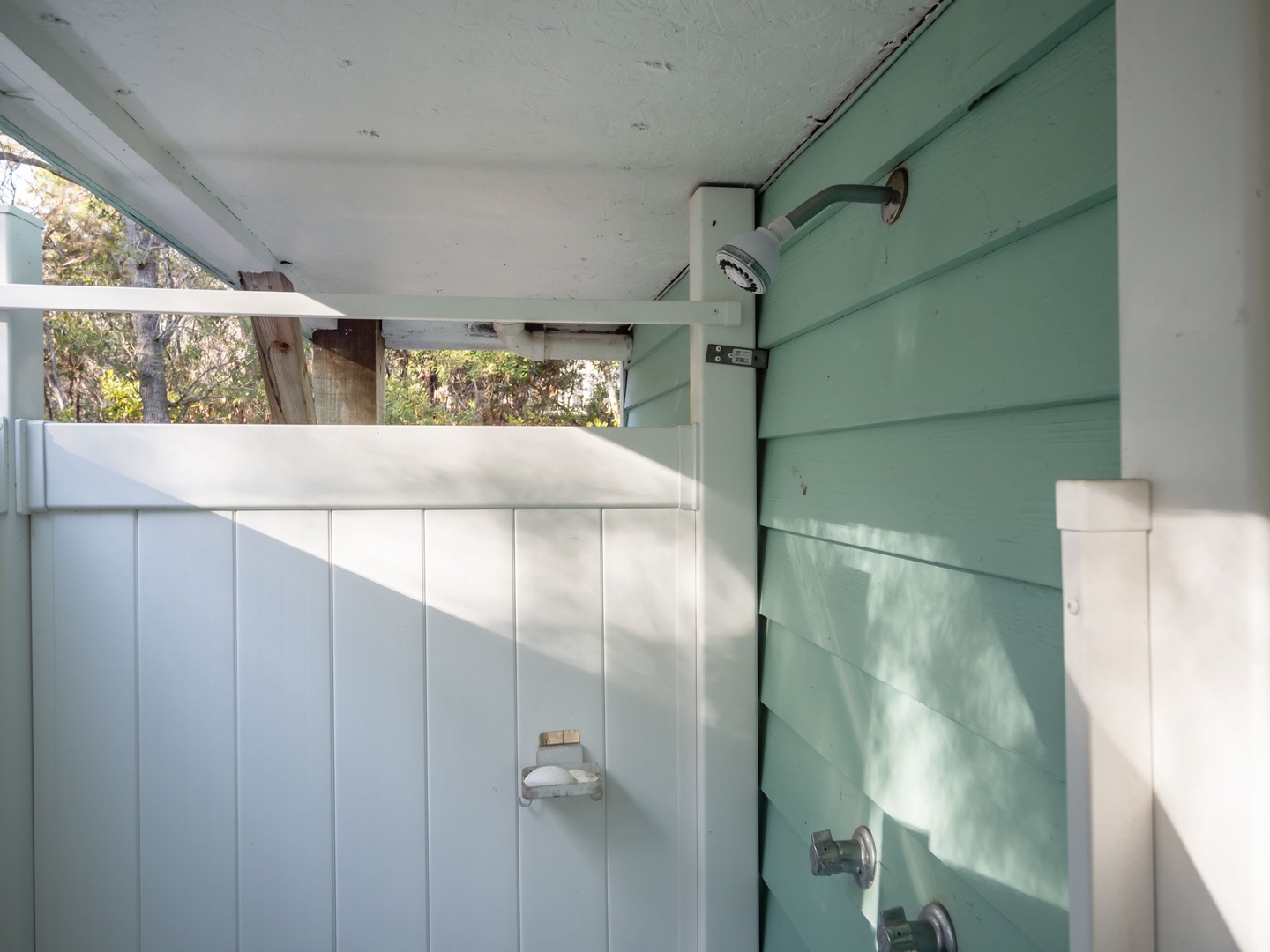 Rinse off under your private outdoor shower, where natural light filters through leafy trees for a refreshing open-air experience.