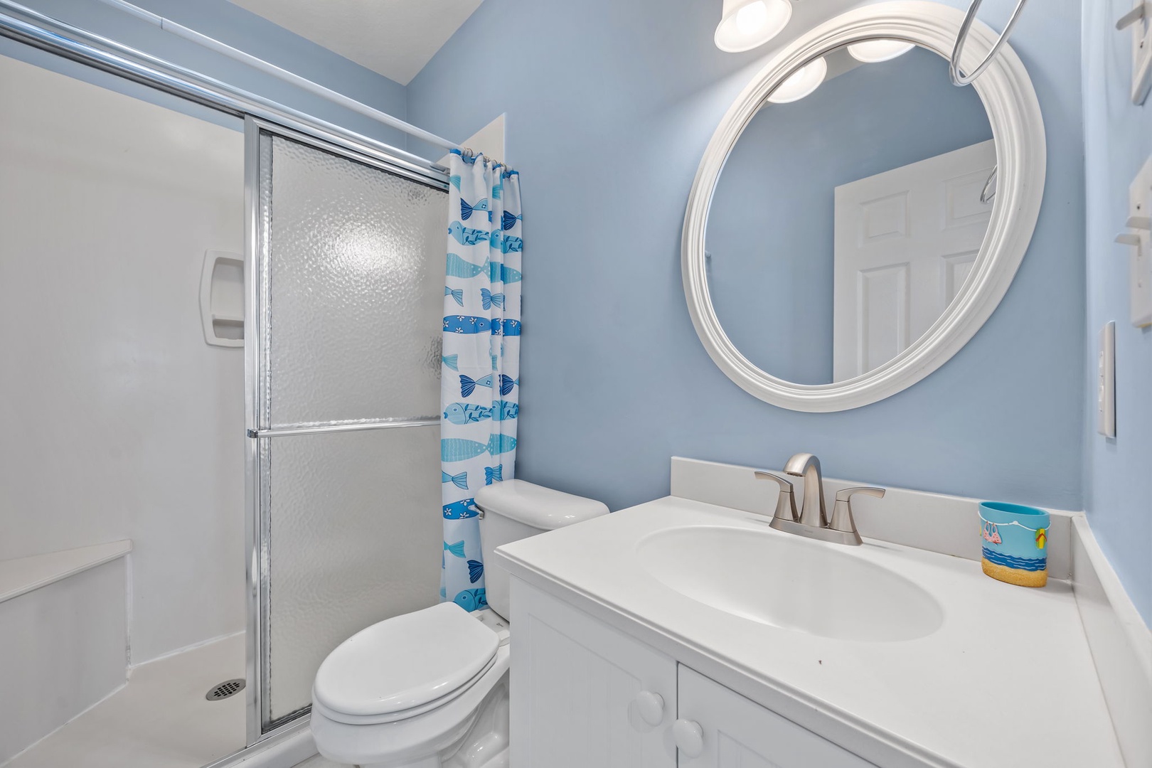 Refresh yourself in this cheerful bathroom with its soothing blue walls, spacious shower, and coastal-themed touches that make your morning routine feel like a seaside retreat.