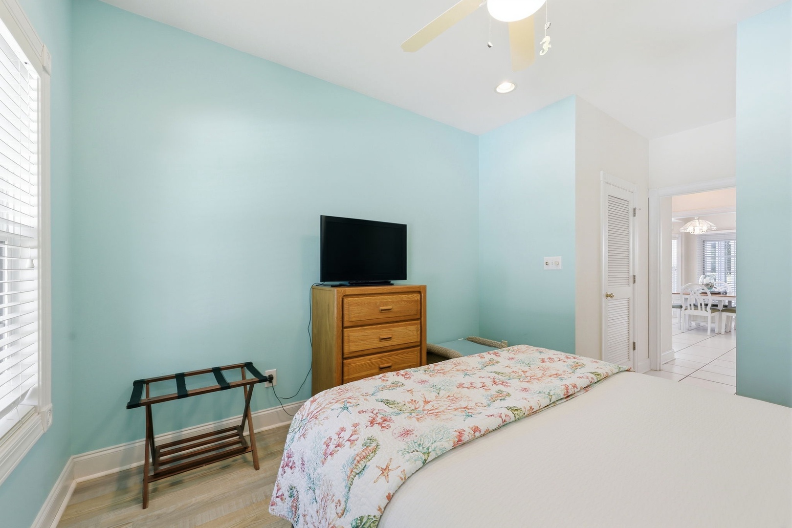 Relax in this serene bedroom with soft blue walls, a cozy bed, and your own flat-screen TV. Enjoy hardwood floors and bright natural light from the window.