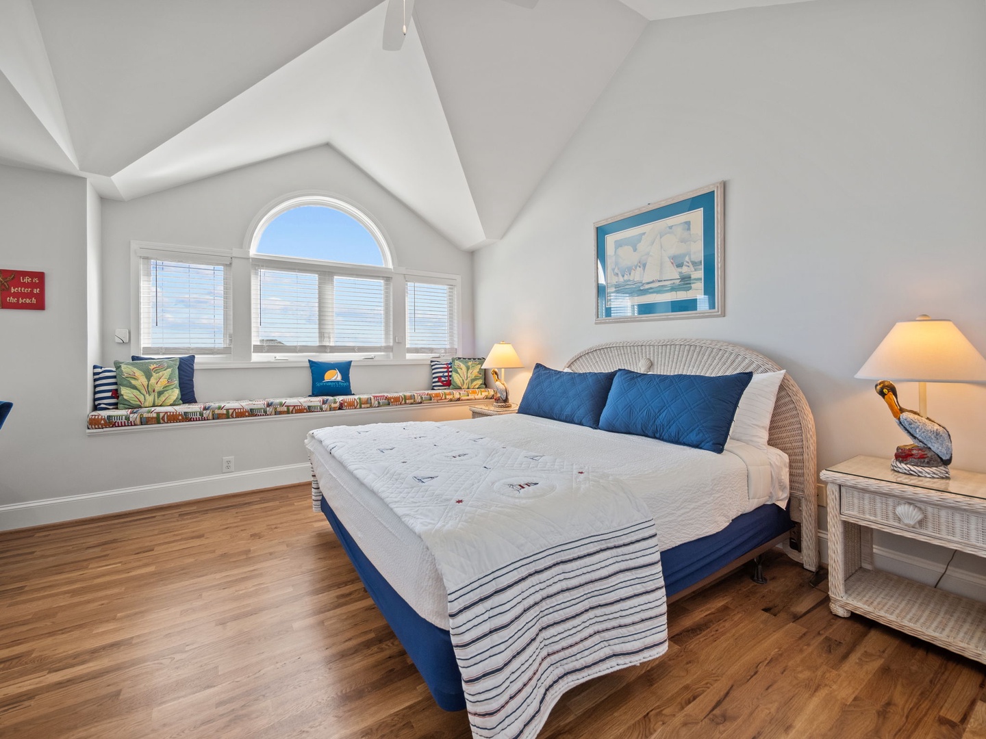 Wake up to natural light streaming through your arched window in this charming coastal bedroom, complete with a cozy reading nook.