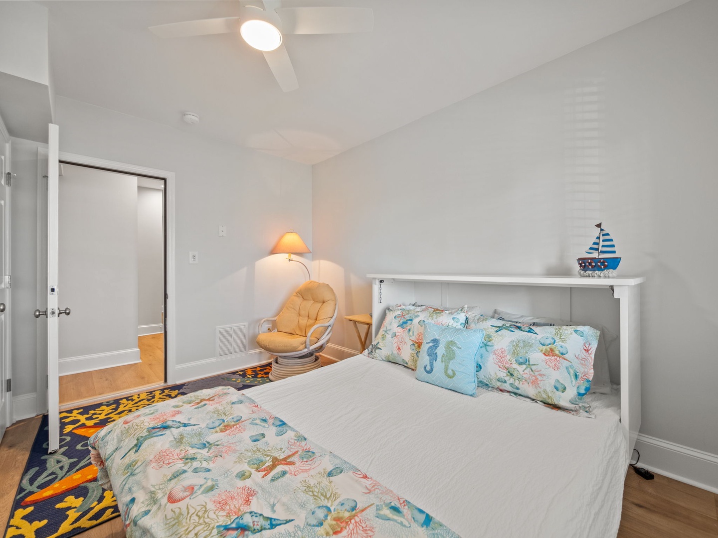 Drift off in your coastal-themed bedroom with whimsical ocean bedding and a cozy reading chair perfect for evening relaxation.