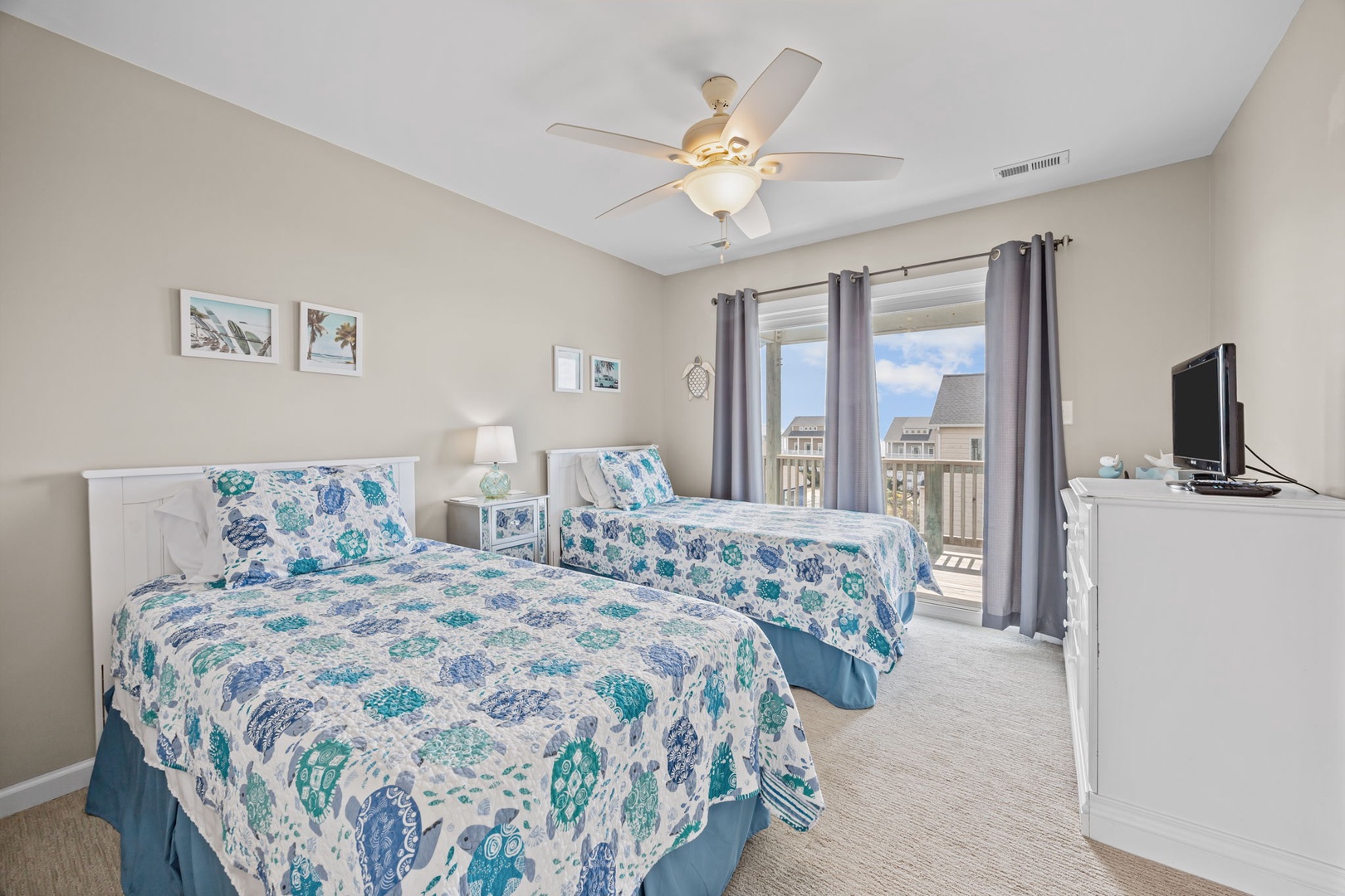 Two comfortable beds await you in this bright bedroom with calming coastal decor and your own balcony access.