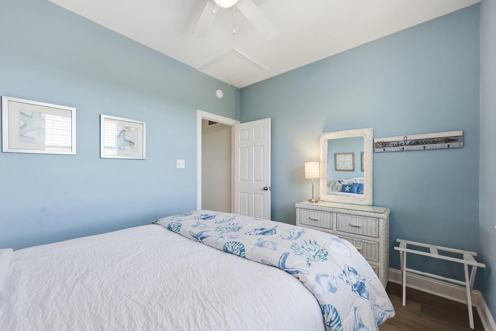 Picture yourself unwinding in this serene coastal bedroom, where soft blue walls and beach-inspired decor invite peaceful slumber after a day of adventure.
