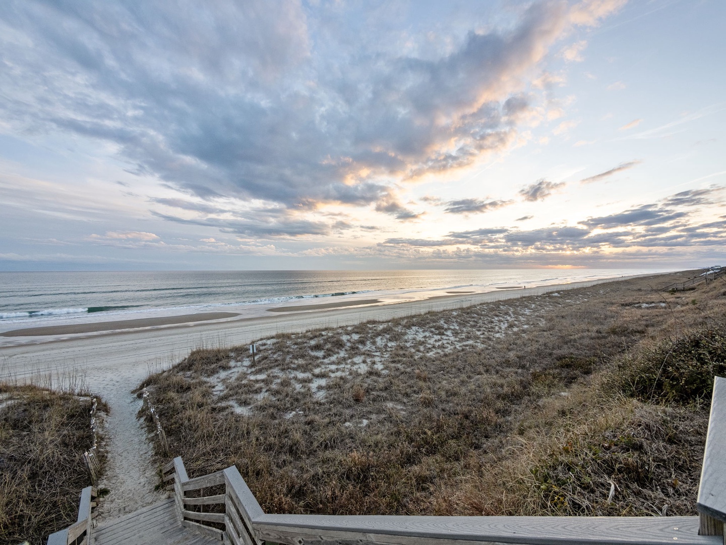 Stunning beachfront location with dramatic evening sky painting the horizon in soft pastels over pristine sandy shores.
