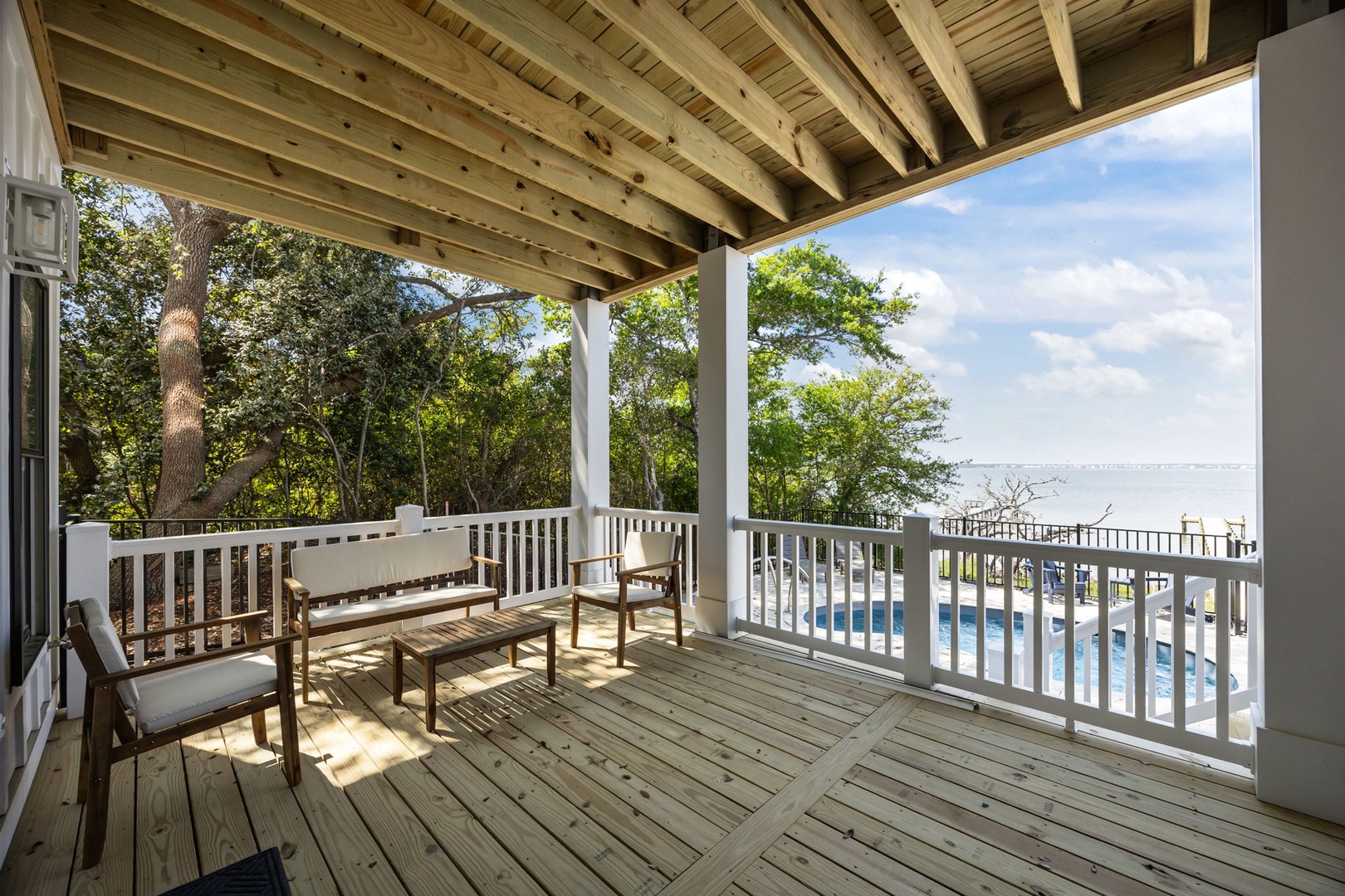 Your private balcony offers serene pool and water views through the trees, where morning coffee feels magical.
