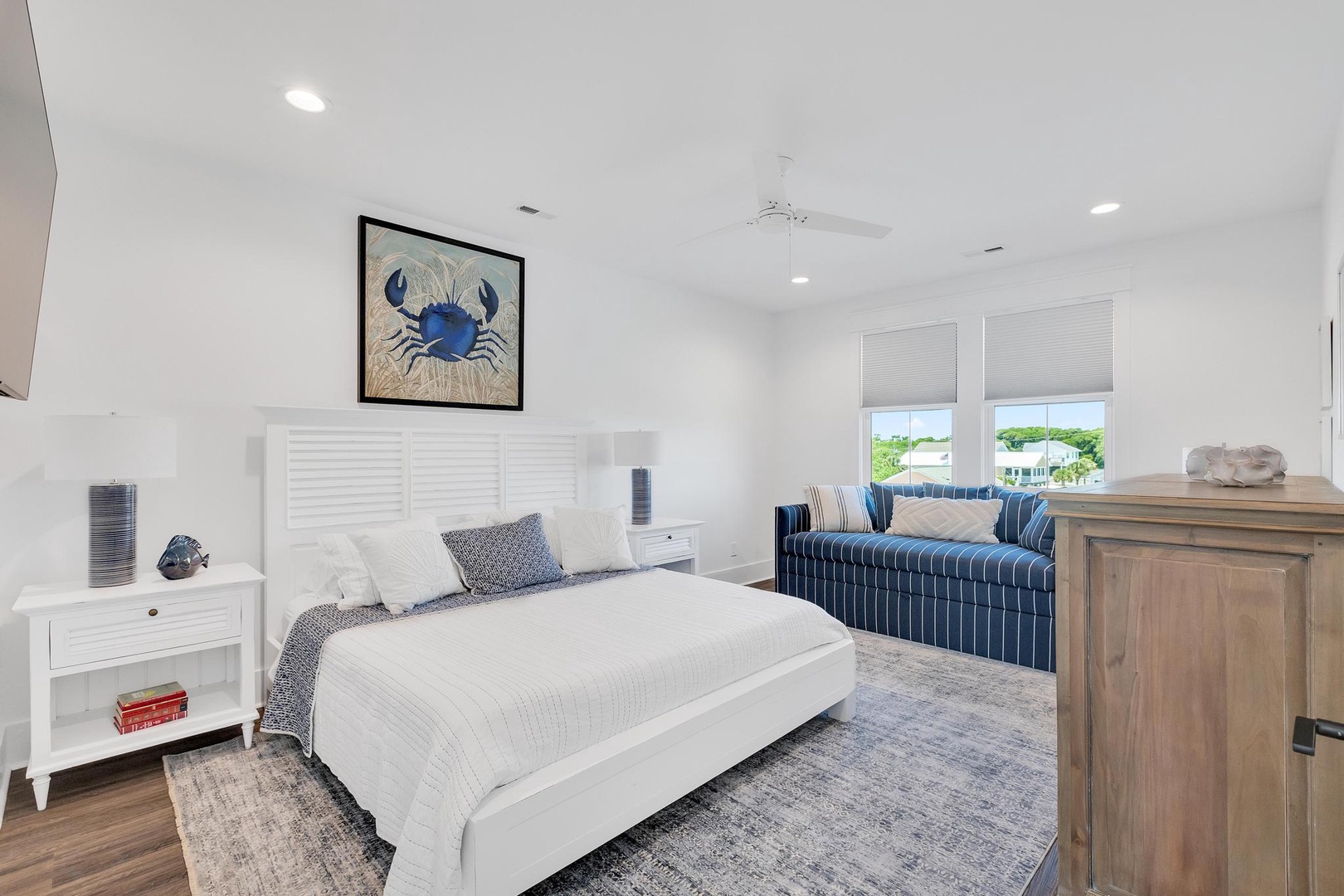 Sink into crisp white linens and coastal charm in your serene retreat, where nautical touches and a plush sofa invite you to unwind completely.