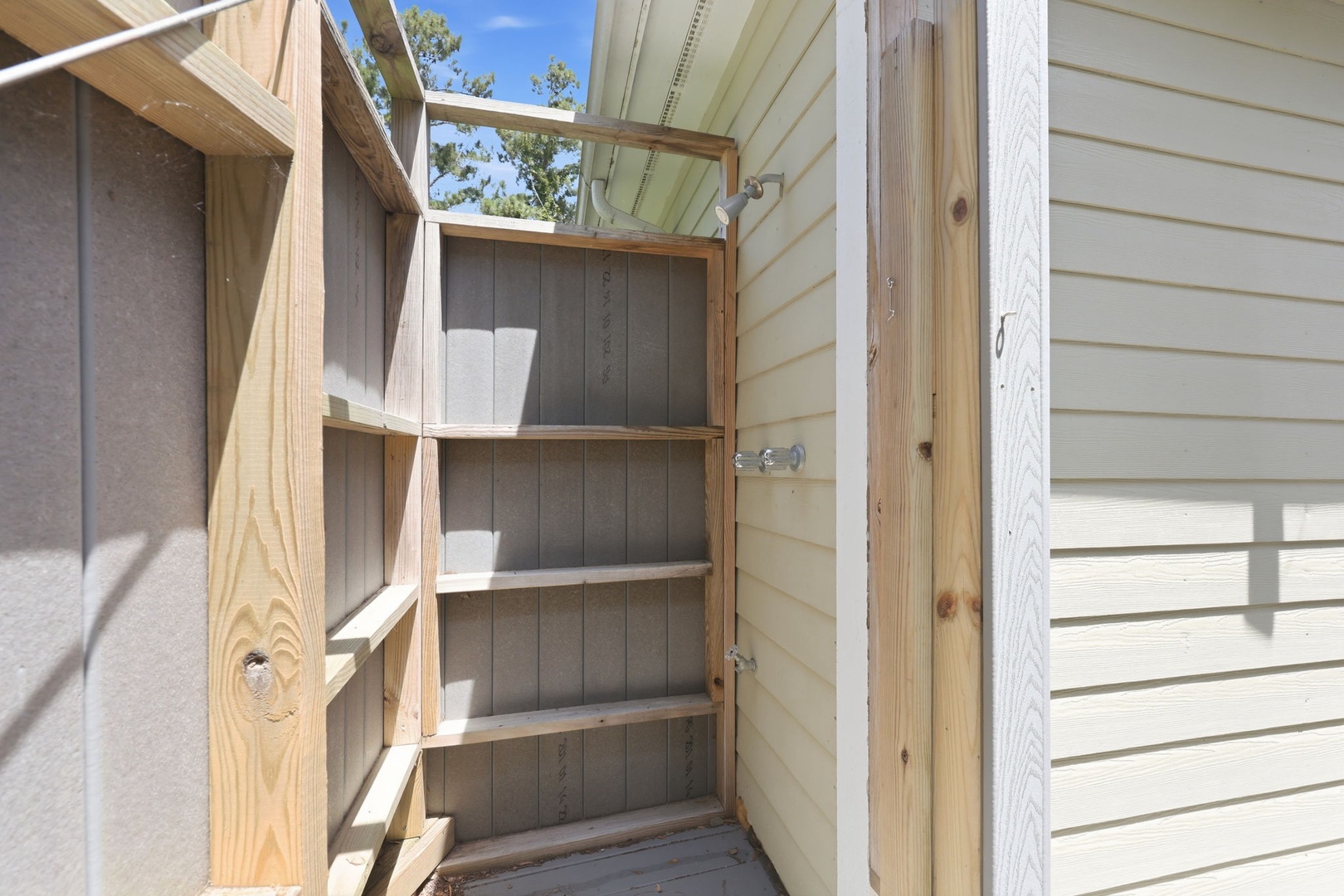 This outdoor storage cabinet provides convenient space for your belongings, nestled beside the property with open-air accessibility and natural light from the skylight above.