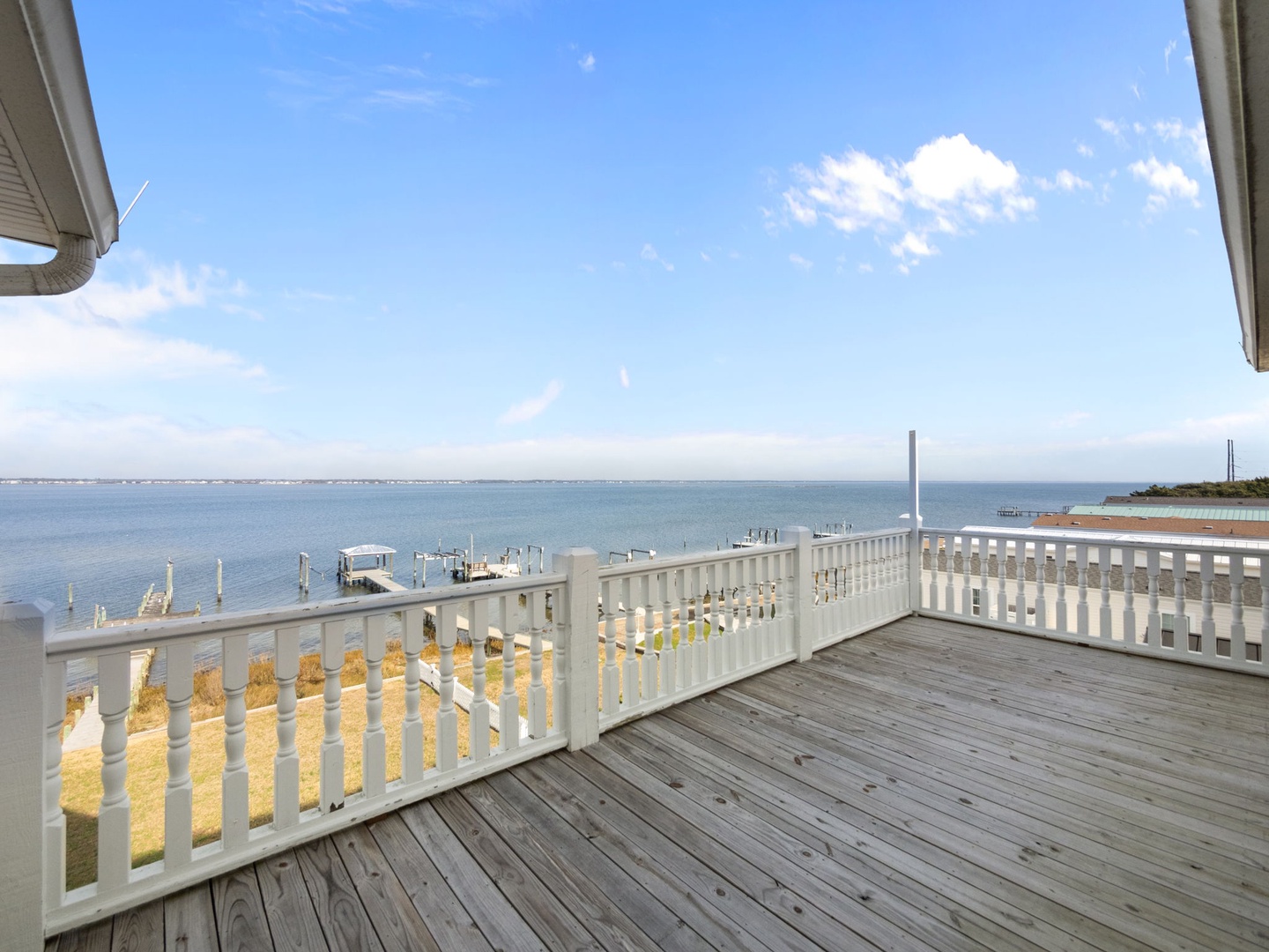 Your private deck overlooks peaceful waters and marina, where mornings begin with gentle waves and endless blue skies stretching to the horizon.