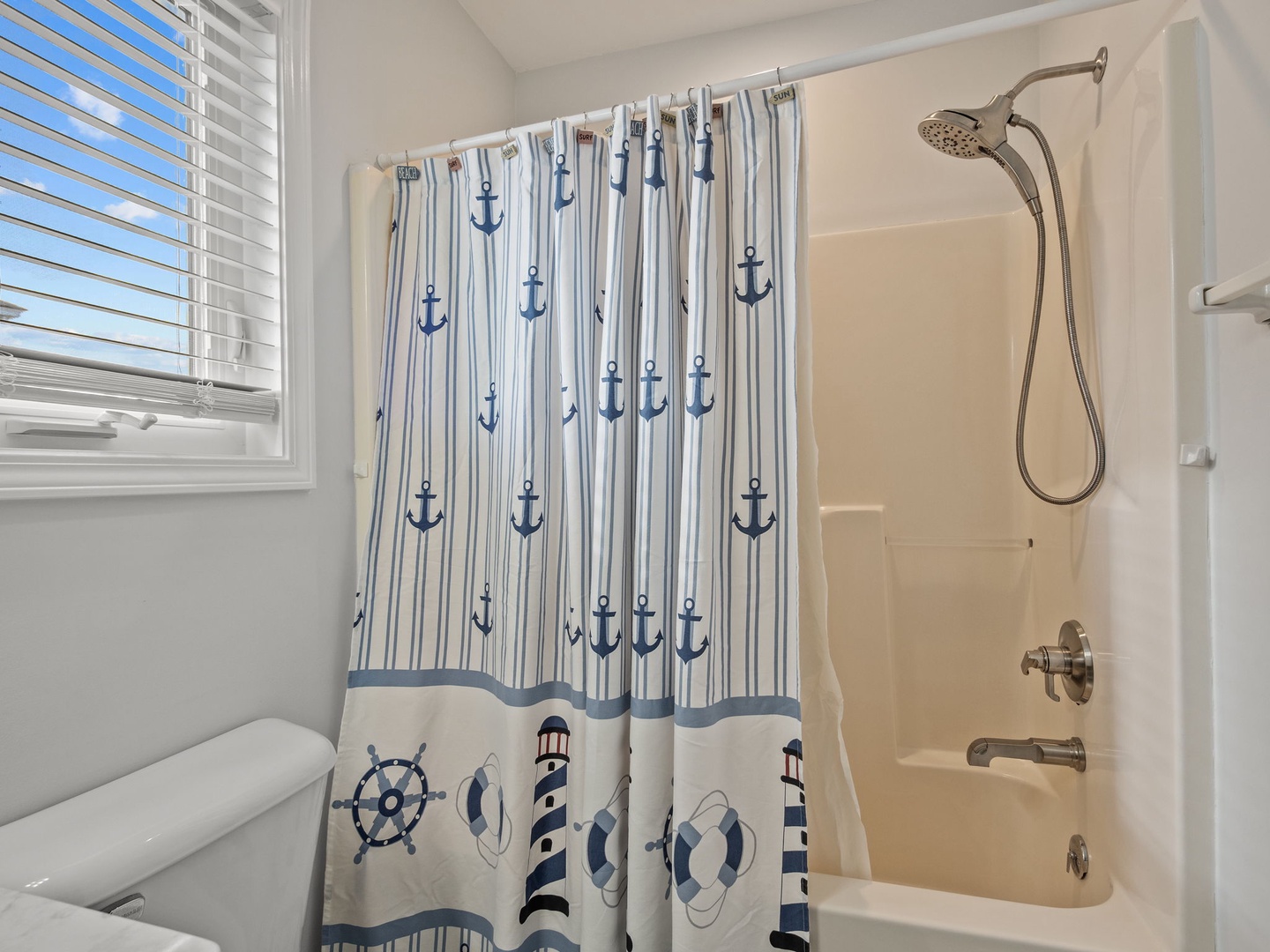 Step into your nautical-themed bathroom where a charming anchor-patterned shower curtain sets the coastal mood for refreshing morning routines.