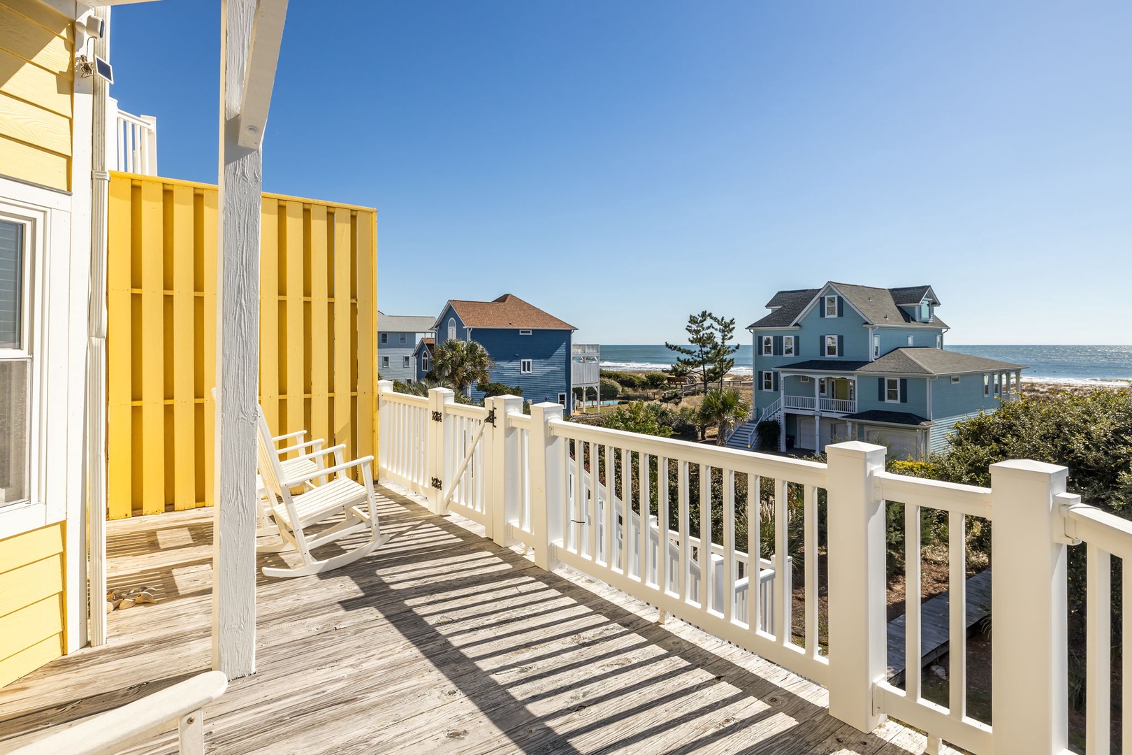 Soak up coastal charm on your private deck with ocean views and colorful beach houses as your backdrop.