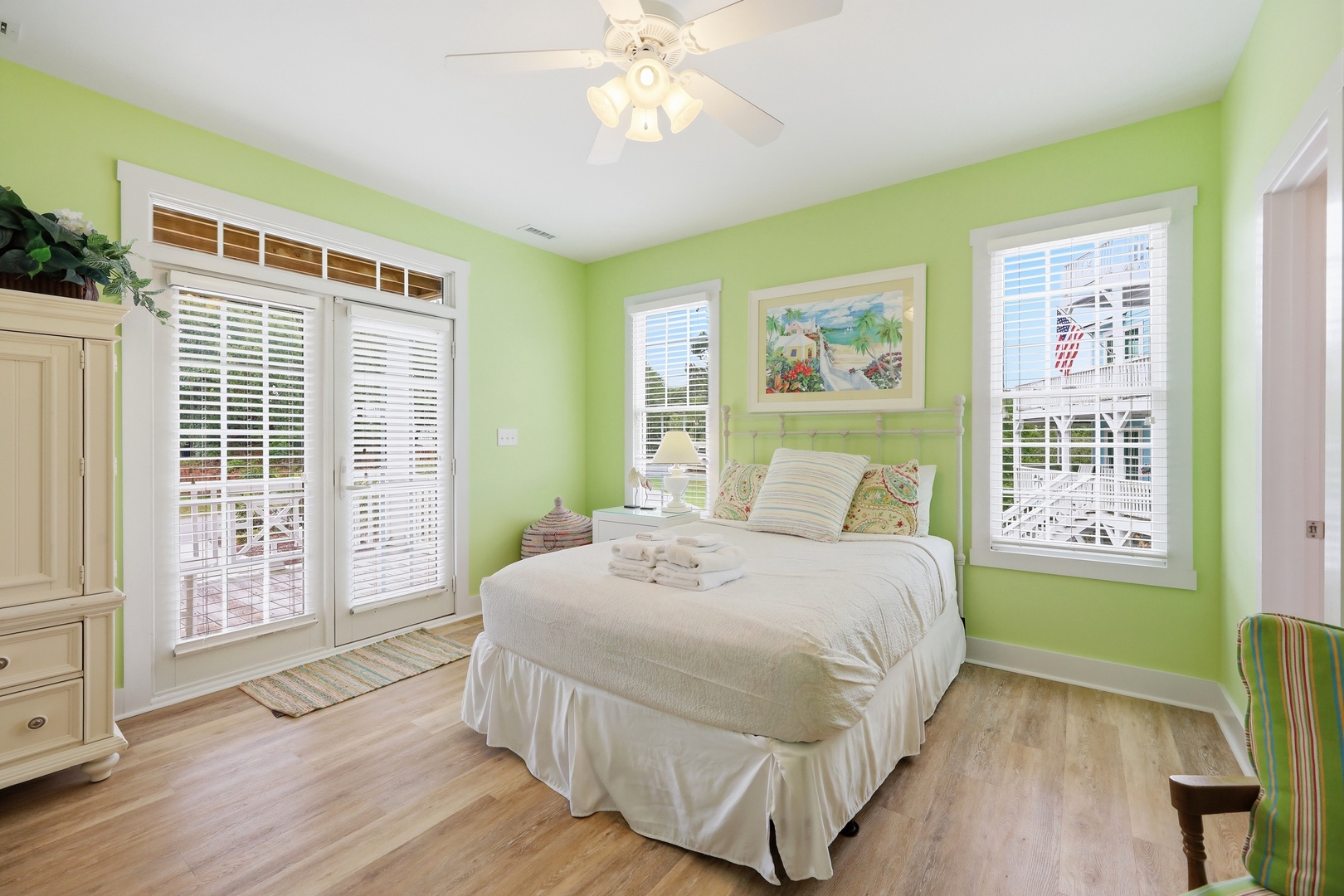 Step into your cheerful coastal retreat with bright green walls, fresh white linens, and a balcony door opening to sunny outdoor relaxation. You'll rest easy in this inviting, naturally lit space.