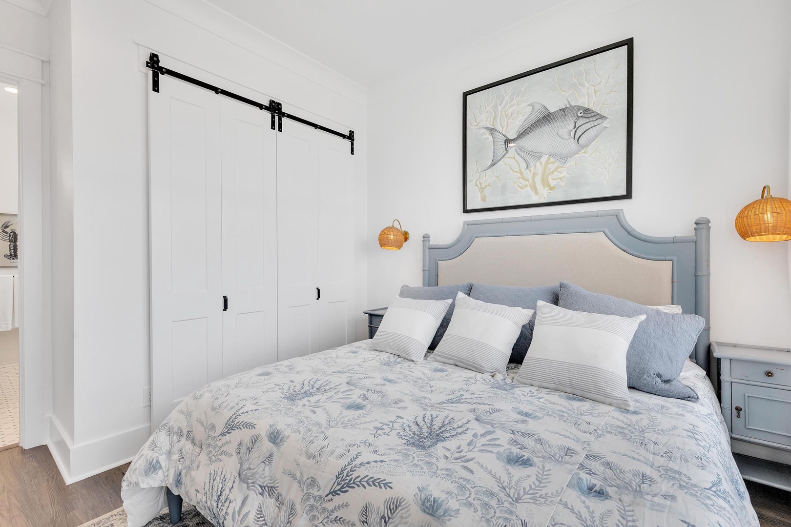 Drift off in this coastal-inspired bedroom featuring a barn door accent and ocean-themed decor that brings beachside tranquility to your stay.