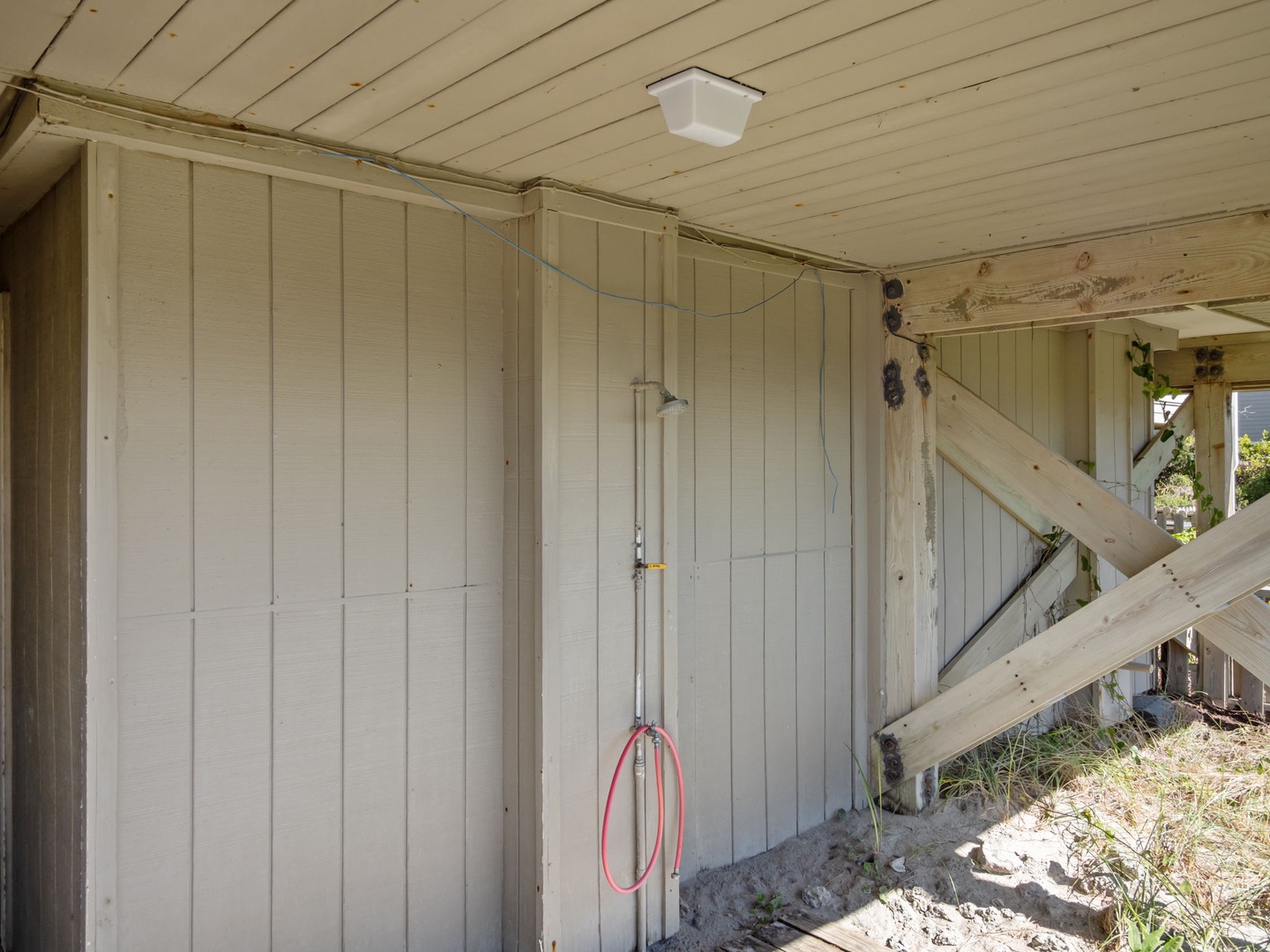 This rustic outdoor shower features natural wood walls and ceiling with a simple overhead fixture for refreshing rinses.