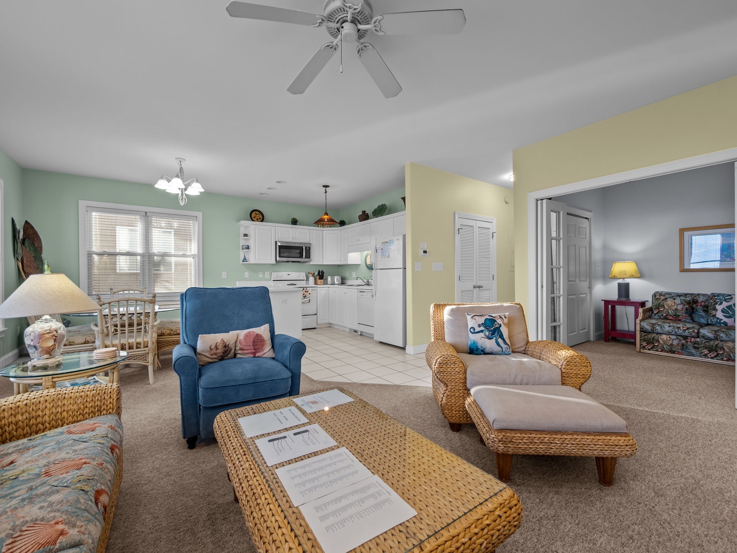 Relax in your spacious open-plan living area with comfortable seating, ceiling fan, and fully equipped kitchen for easy meal prep.