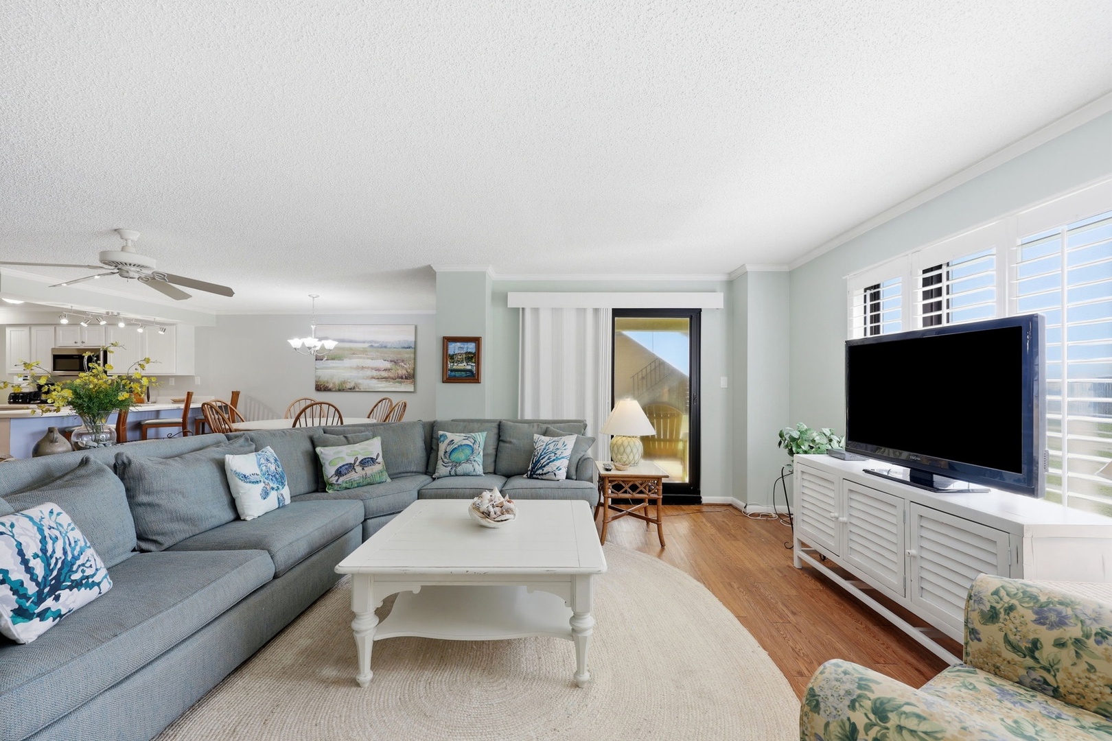 Settle into this airy coastal living room where soft blues and whites create your perfect beach retreat. Relax on the spacious sectional as natural light fills your open-concept space.